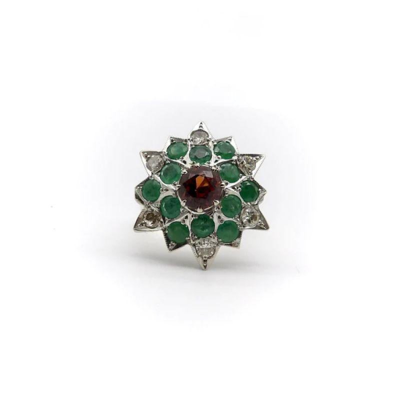 This is a stunning 18k white and yellow gold ring, fashioned in the shape of a starburst or flower with 12 points. The center stone is a dazzling 6.5 mm spessartite garnet with beautiful deep orange hues. Surrounding it are twelve 3.5mm natural