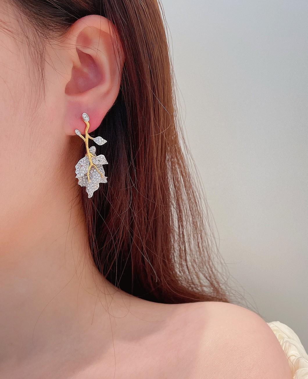 Boucles d'oreilles feuilles en or blanc 18K et diamants multi-tons

Poids total : 11,22 g
Poids net de l'or : 10.692 g
Pierres principales : 8 diamants, 0.280 CT
Pierres secondaires : 294 diamants, 2.360 CT

Ces exquises boucles d'oreilles pendantes
