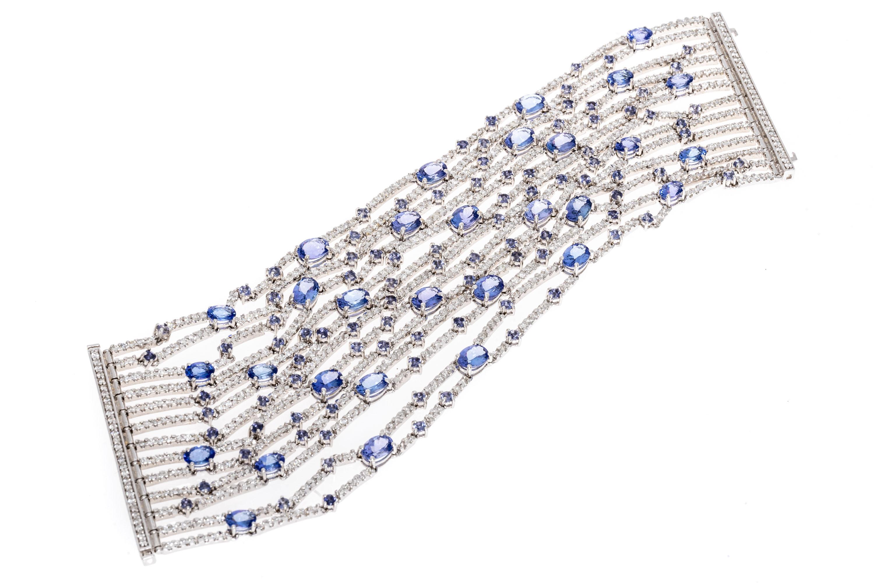18k white gold bracelet. This absolutely spectacular bracelet is a flexible, multi-row line style, encompassing tanzanite and diamonds. 
The tanzanite stones are comprised of several variations. Starting with the small round faceted stones, they are