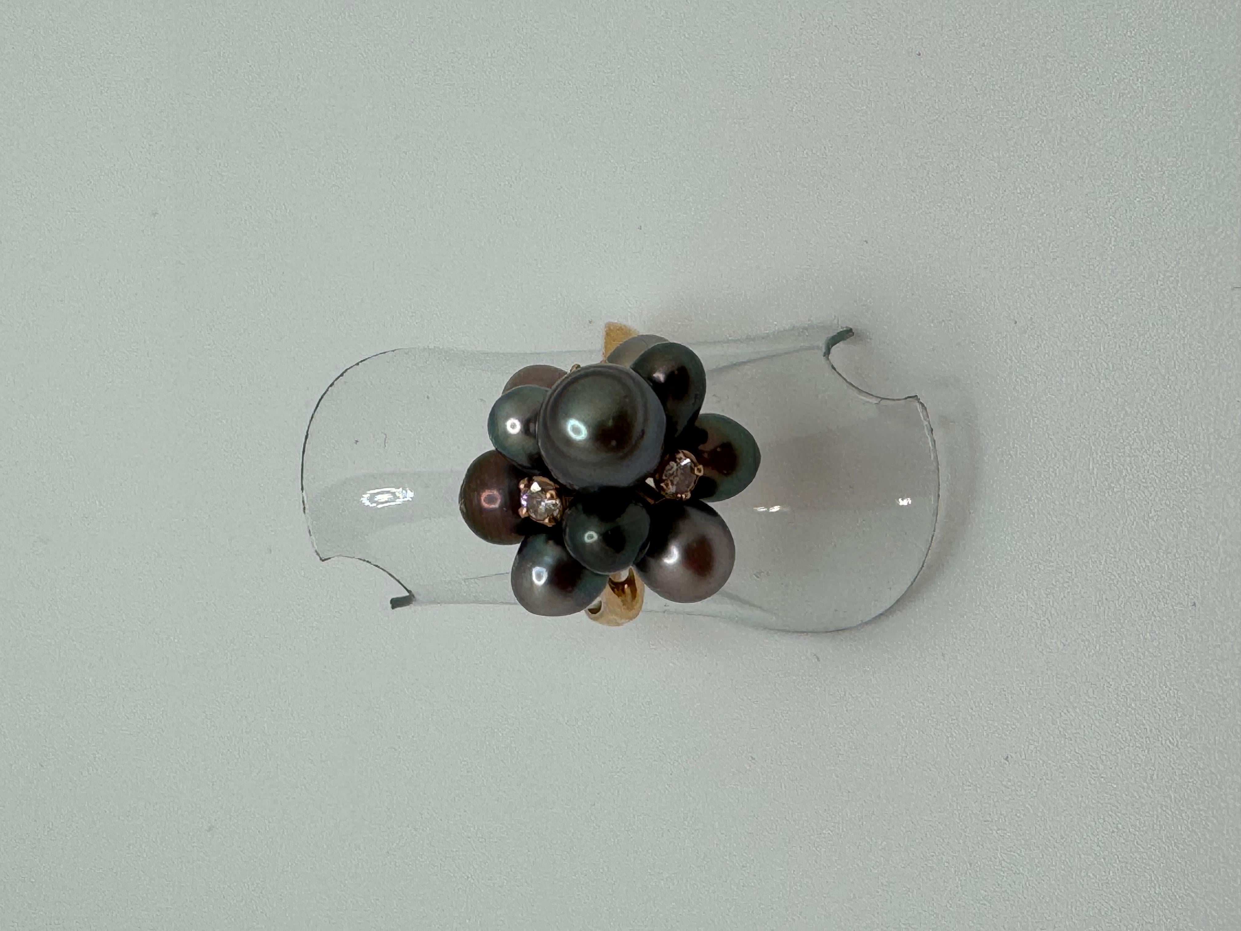 Questo splendido anello da cocktail è realizzato in oro 18 carati e presenta un'elegante combinazione di diamanti e perle grigie. Il design include tre diamanti scintillanti, ciascuno di circa 2,2 mm, che aggiungono un tocco di brillantezza. Intorno