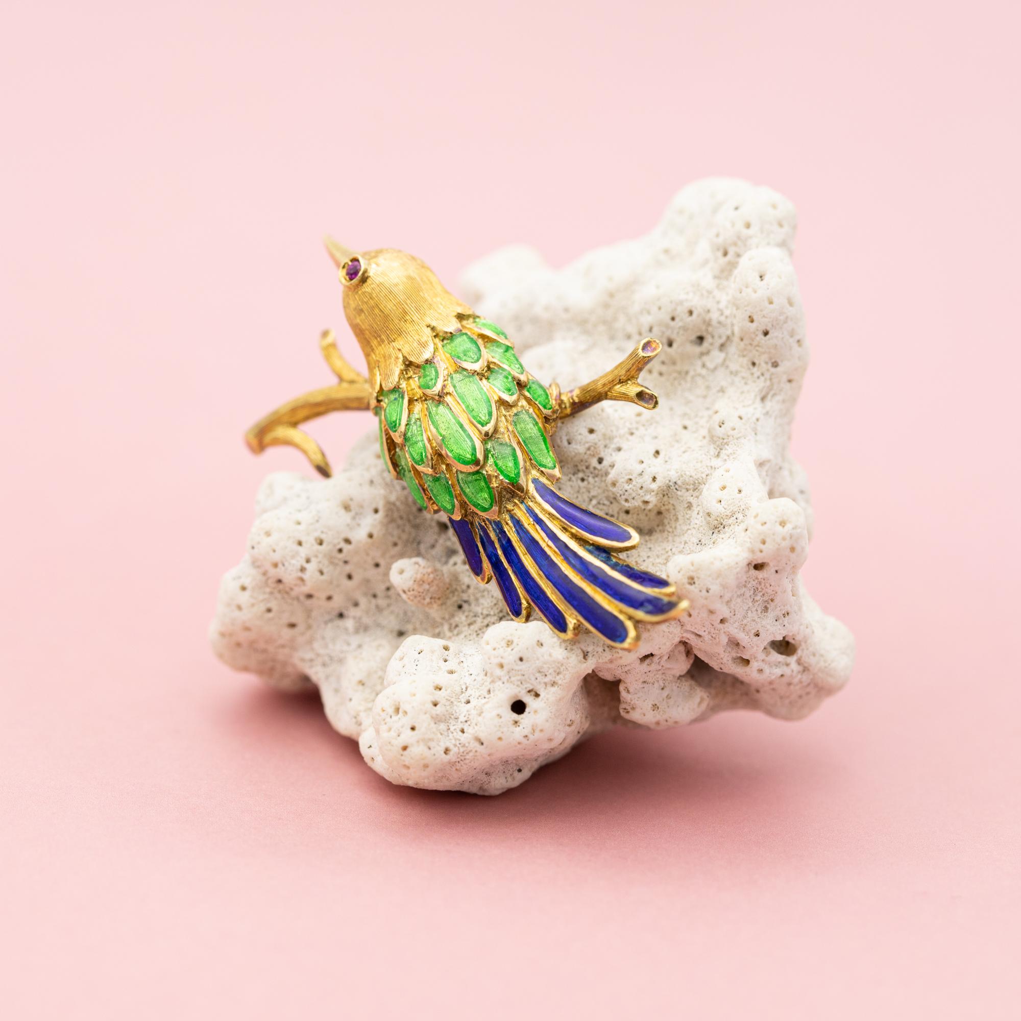 For sale is this very cute colourful bird brooch. This 18k yellow gold animal is set with a lovely small ruby eye and decorated with Blue, Green enamel feathers. Two of the blue enamel feathers are a bit damaged, the top coat of the enamel is a bit