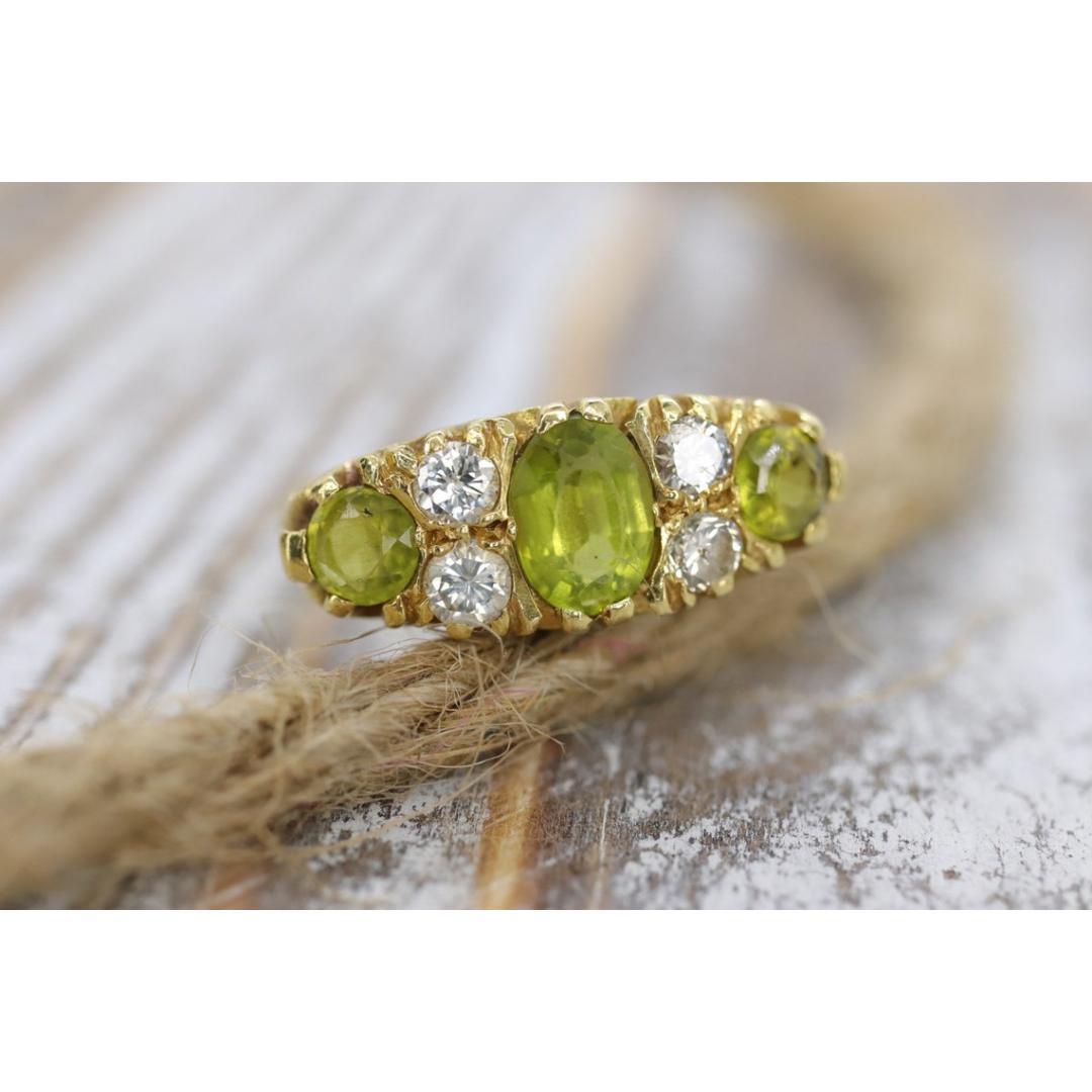 Vintage from the 1970s
Materials: Stone
Gemstone: Peridot
Gem Color: Colorless

Band Color: Gold

18K yellow gold, peridot & diamond ring


Details:
Diamonds 3mm diameter -- 4 x 0.10ct = 0.40ct
Center Peridot 5 mm x 7mm approx
Accent Peridots: 4mm