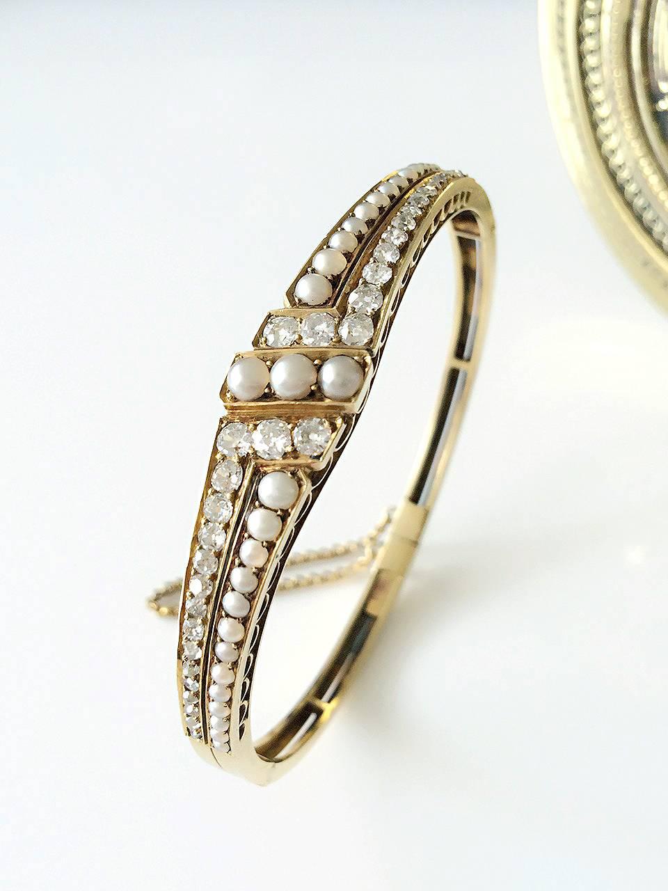 A late 19th century 18ct gold split pearl and diamond hinged bangle. The split pearl slanted line, to the graduated vari-cut diamond and split pearl geometric sides and openwork half-bangle. Estimated total diamond weight 1.50cts, H-I colour, SI