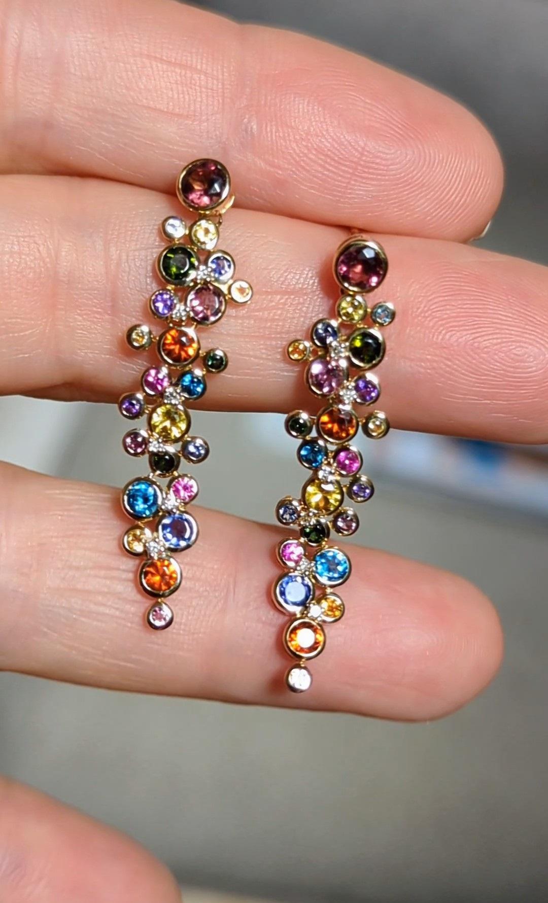 Diese mehrfarbigen Edelsteinohrringe sind aus länglichen Edelsteingruppen und Diamanten gefertigt. Die Farbedelsteine sind in der Lünette gefasst, die Diamanten in der Zange. Diese Ohrringe sind von den Sternbildern inspiriert - und sie sind klein,
