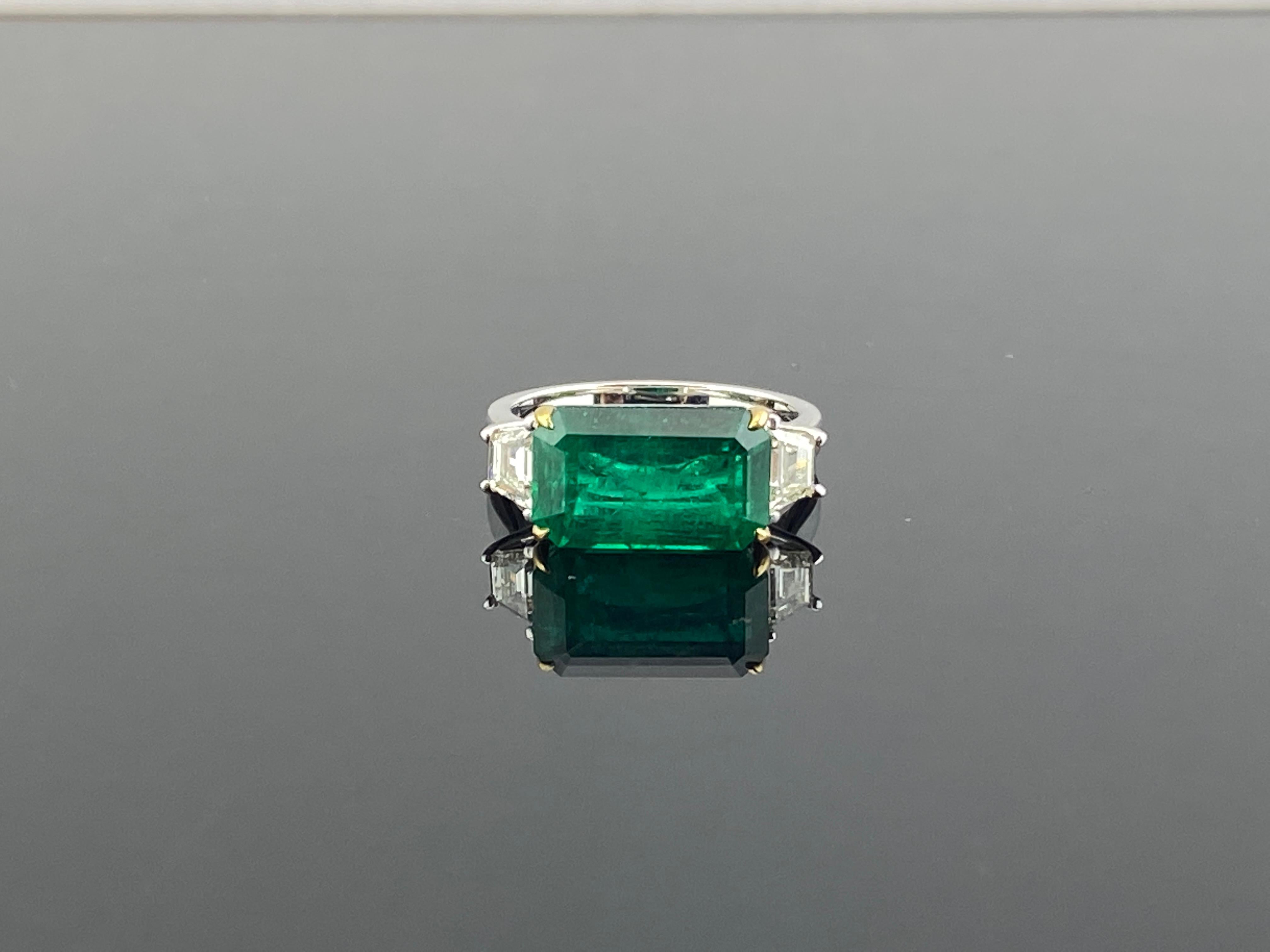 This ring is a simple but elegant with its high quality 4.64 carat emerald stone in the center of the ring cushioned with two trapezoid cut diamonds on its sides. . The Emerald is of Zambian origin an has a beautiful luster and a vivid green color.