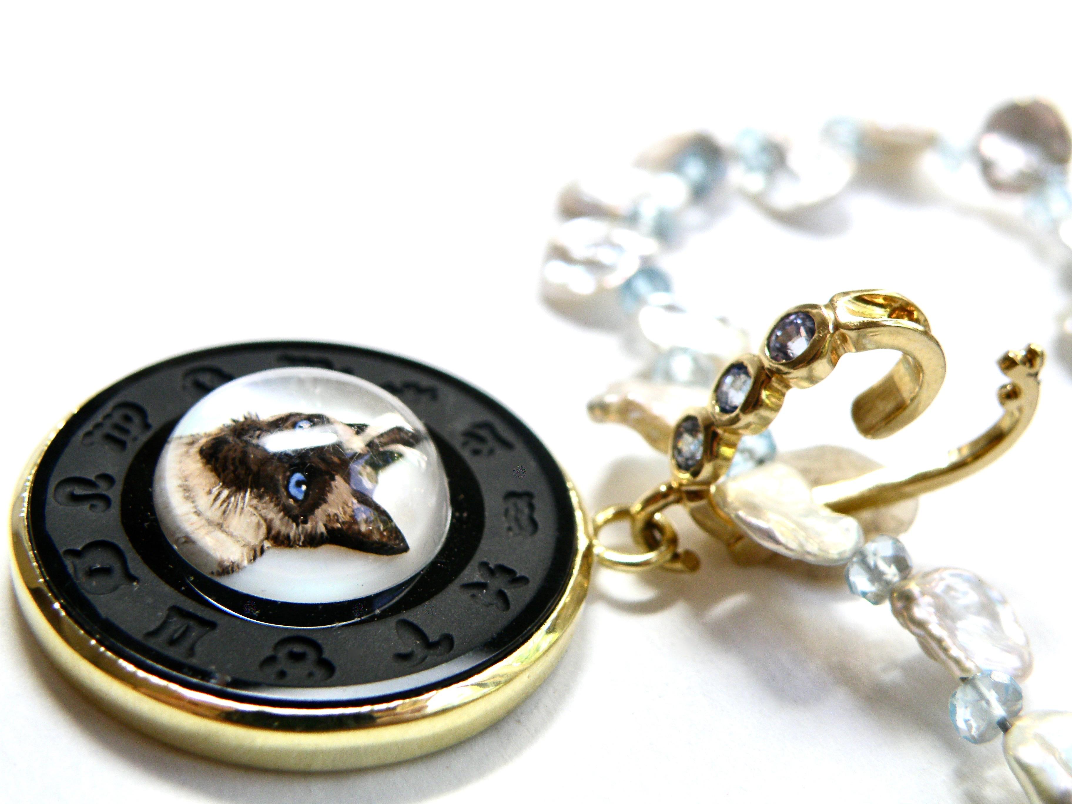 18k gold bezeled reversable crystal carving of a siamese cat framed in unique black onyx zodiac carving. 30mm round