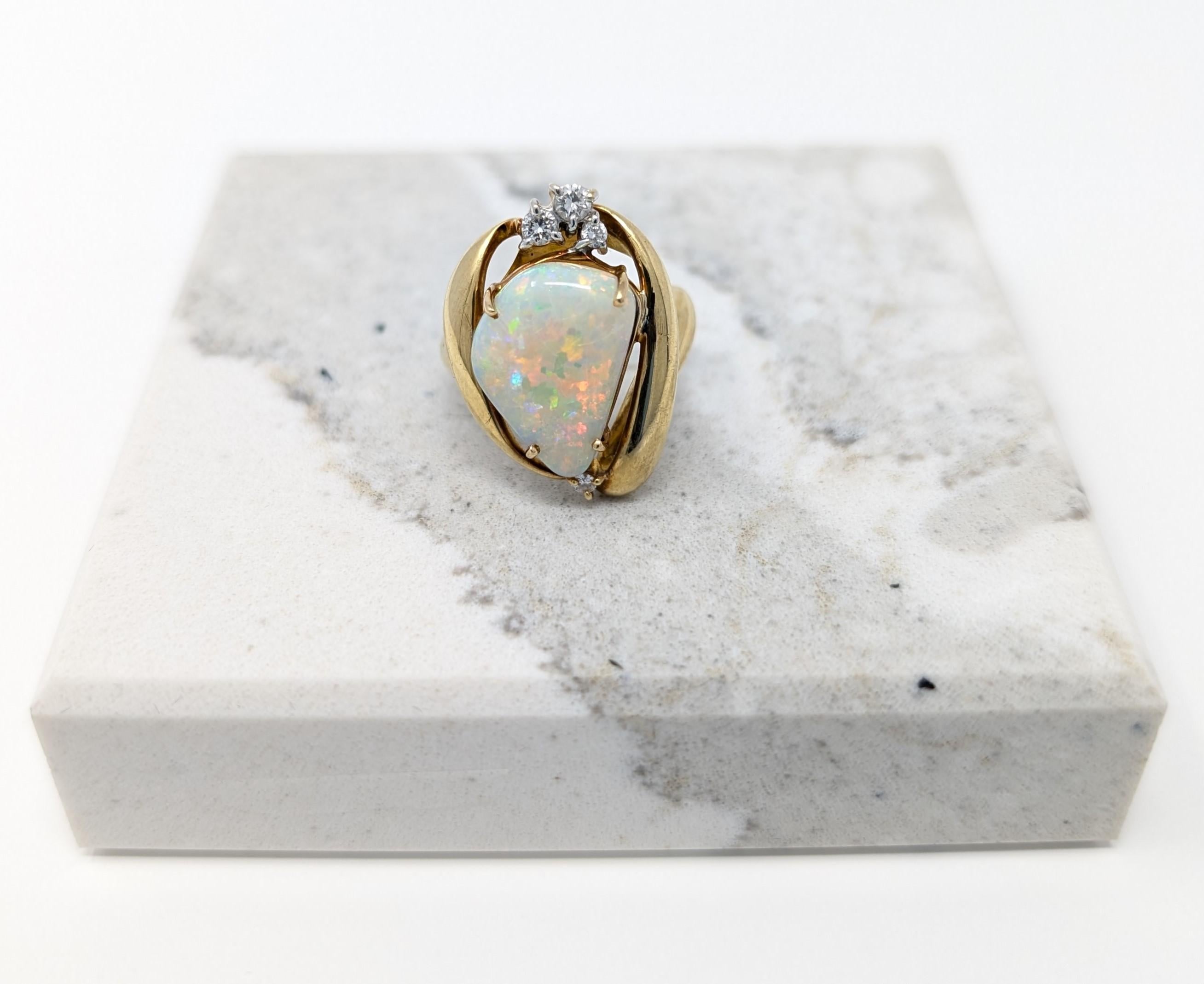 Eye catching 18k yellow gold ring featuring a mesmerizing large opal cabochon accented by dazzling diamonds. Best fits for a size 5.5 finger and is stamped K18 on the interior of the band. Measures .65 inch in width by .95 inch in length, measures