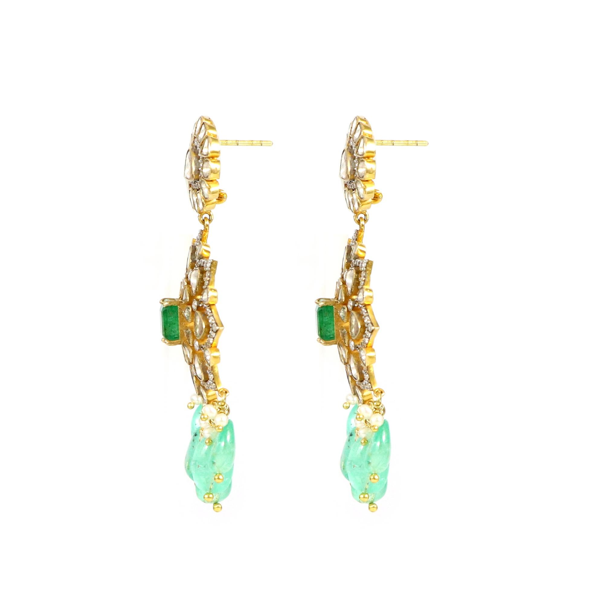 Behold this stunning pair of meticulously crafted earrings, a symphony of emeralds, polki diamonds, and 18K gold with an open setting. These earrings stand as a testament to unparalleled elegance and sophistication. With their timeless beauty and