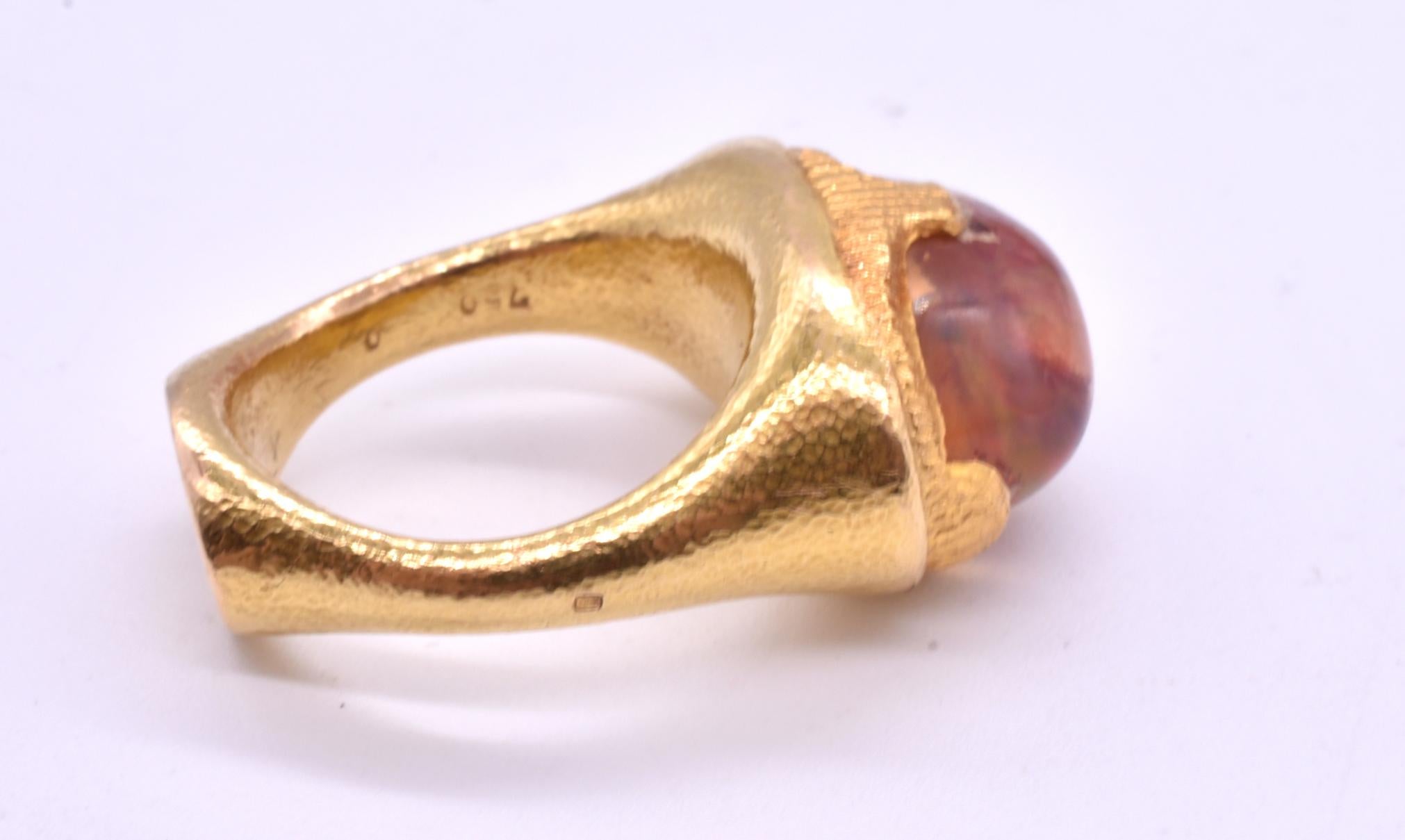 Mesmerizing 18K substantial ring with large fire opal cut en cabochon and mined in Mexico. The fire opal is securely embedded in its solid gold enclosure, an important factor as opals require a setting that is substantial to protect the stone. A