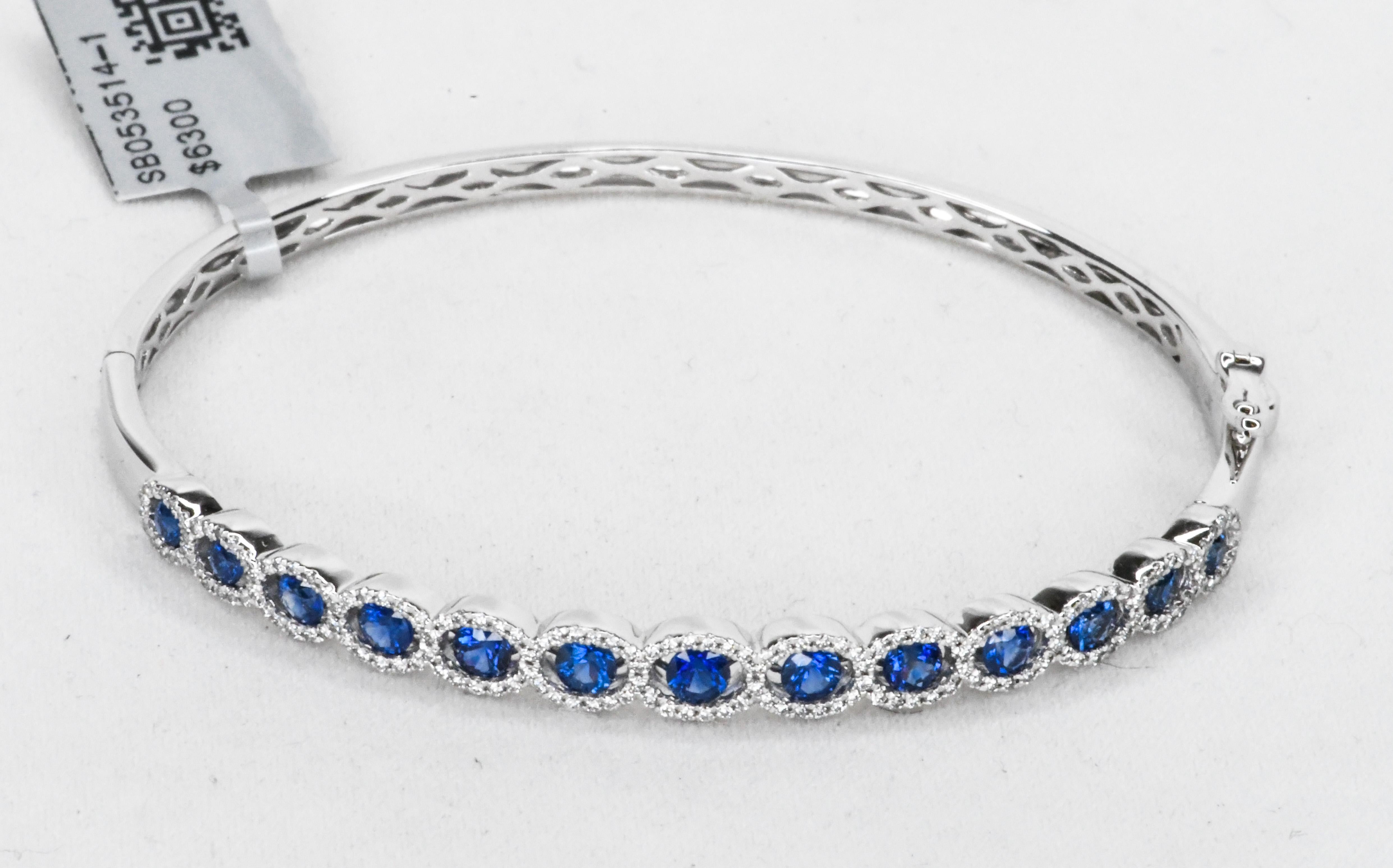 The combination of blue sapphire and white diamonds is perhaps the most sophisticated look in Fine Jewelry!
This hinged bangle bracelet is suitable for every day wear.  From day to night.  Fabricated in 18 karat white gold, it features thirteen