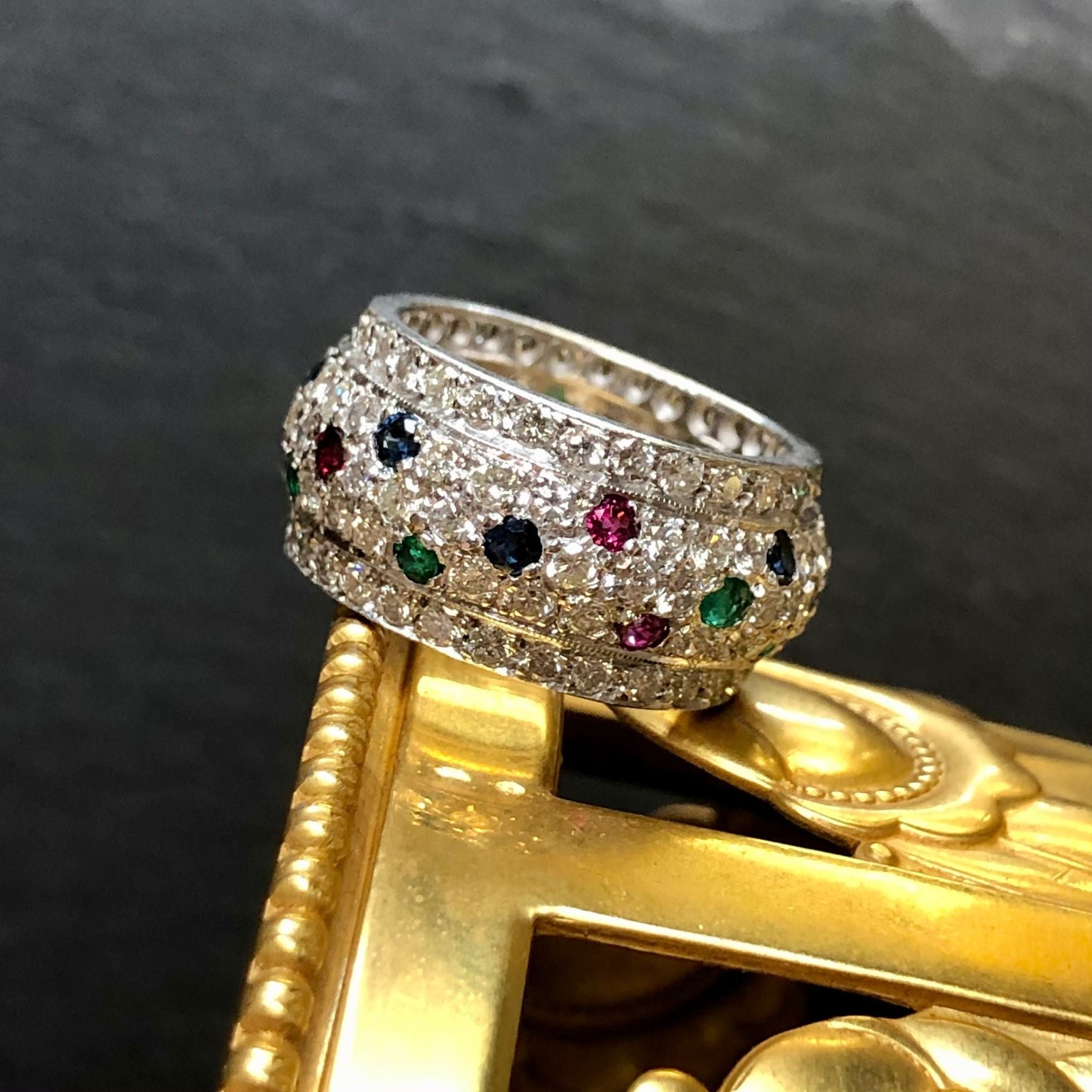 A beautiful slightly domed wide pave diamond band done in 18K white gold set with approximately 3.90ctw in G-J color Vs2-Si1 clarity round diamonds as well as natural rubies, sapphires and emeralds.

Dimensions
.40” wide. Size 6.5.

Condition
All