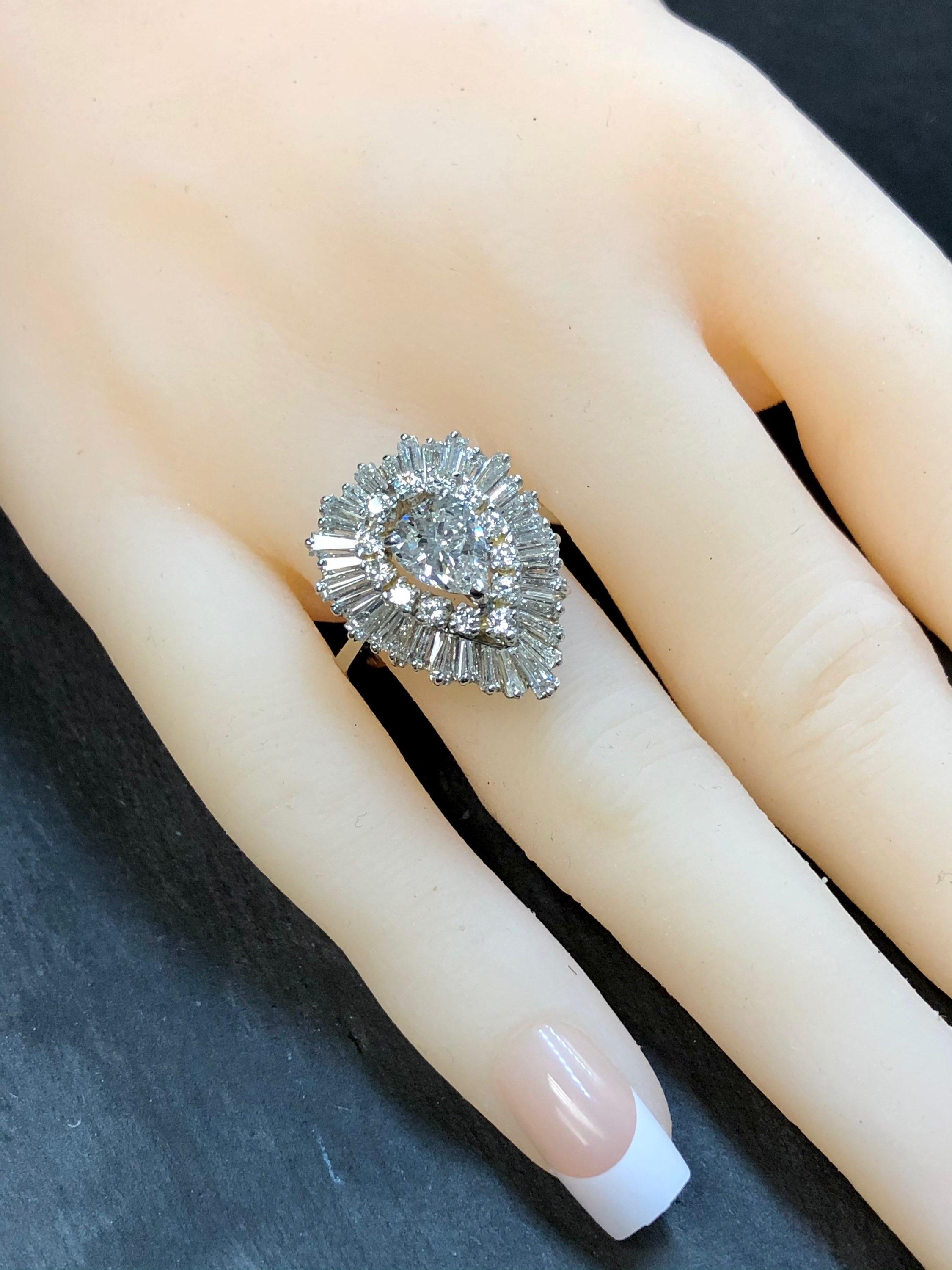 A fabulous vintage ballerina ring done in 18K white gold centered by a 1.29ct pear shape diamond being H in color and Si1 in clarity (GIA report included). Surrounding the center stone is another approximately 3.50cttw in round and tapered baguette