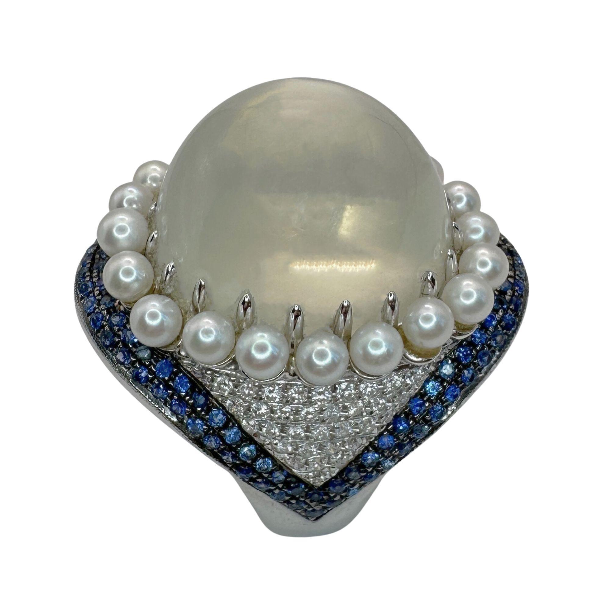 Introducing our 18k Pearl, Diamond, Sapphire and Moonstone Cocktail Ring. Crafted with 18k white gold and featuring 0.42 carats of diamonds, 37.38 carat moonstone center, and 0.82 carats of sapphires, this ring is a true statement piece. In