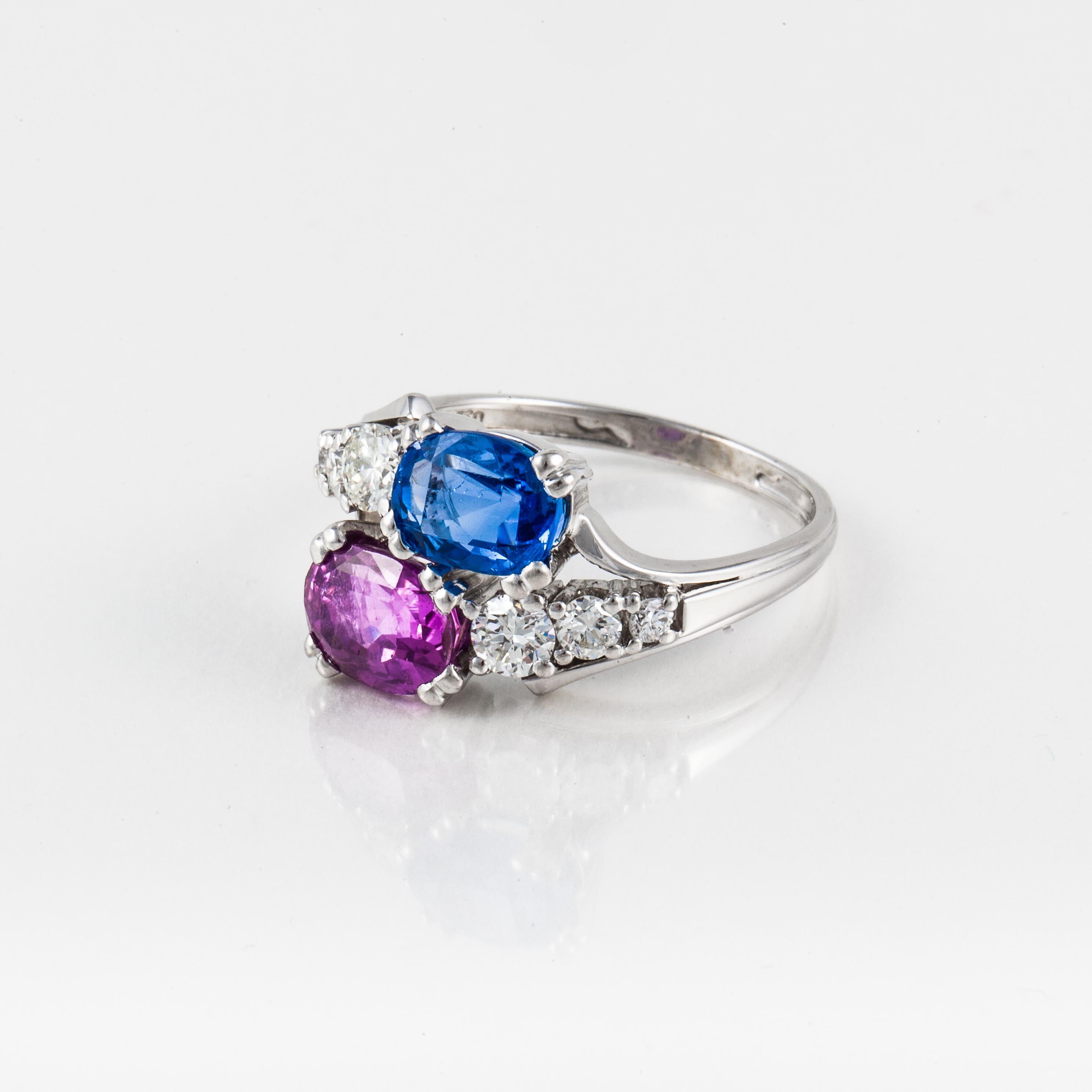 18K white gold bypass ring featuring an oval cut blue sapphire and an oval cut pink sapphire accented with round diamonds. The six round diamonds total 0.75 carats; G-H color and VVS-VS clarity.  Ring is currently a size 8 3/4 and may be sized.  It