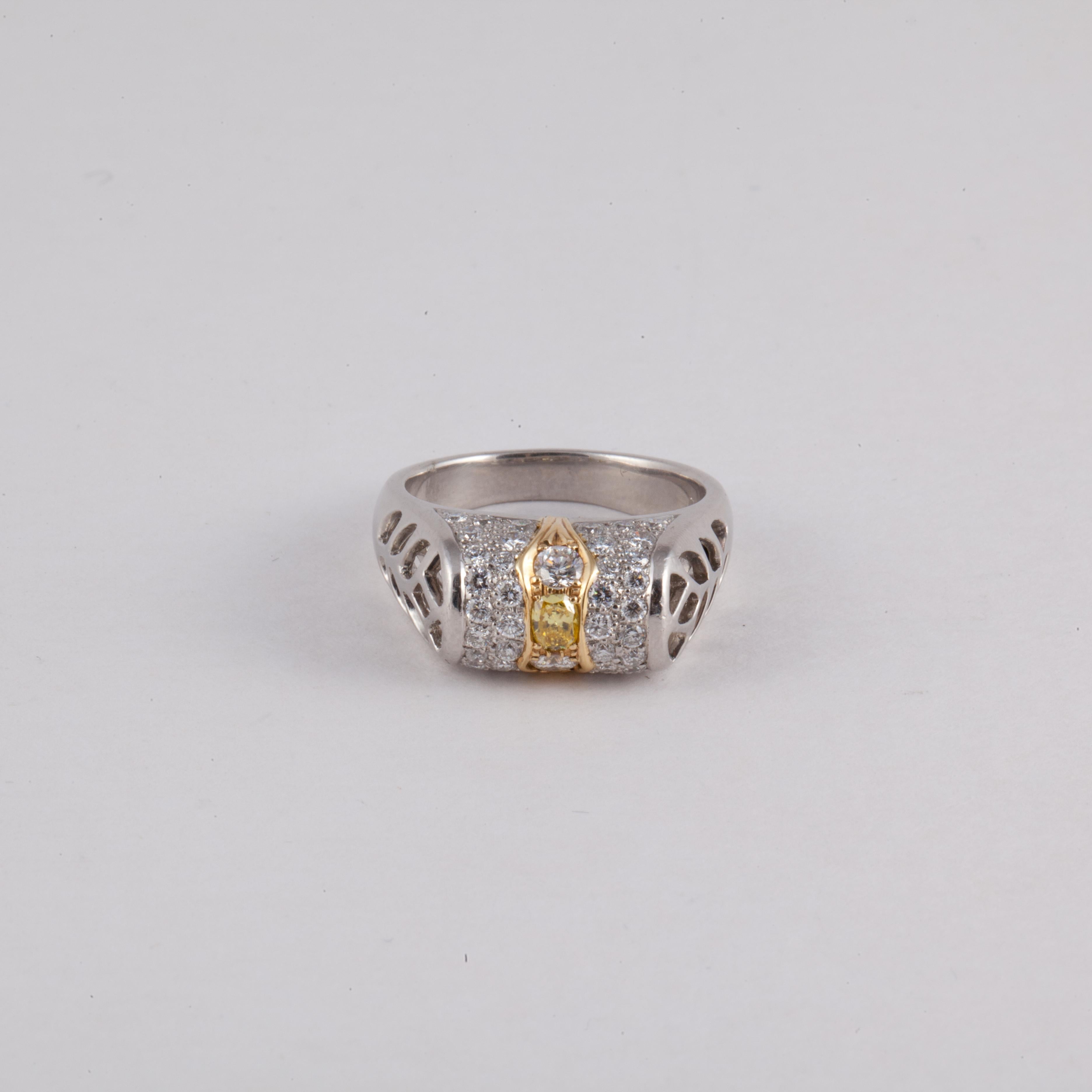 Platinum ring with 18K yellow gold strips on the top featuring an oval canary diamond weighing 0.10 carats.  Surrounding the canary diamond, are 44 round diamonds with a total carat weight of 0.85. Presentation area measures 3/4 inches by 5/16