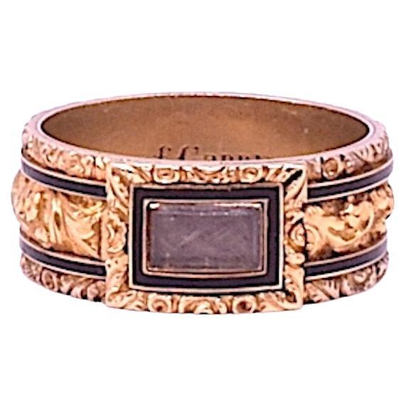 Exceptional mourning band of the Regency period, with stripes of black enamel bordered with gold trim sandwiched between chased floral borders. The inscription reads 