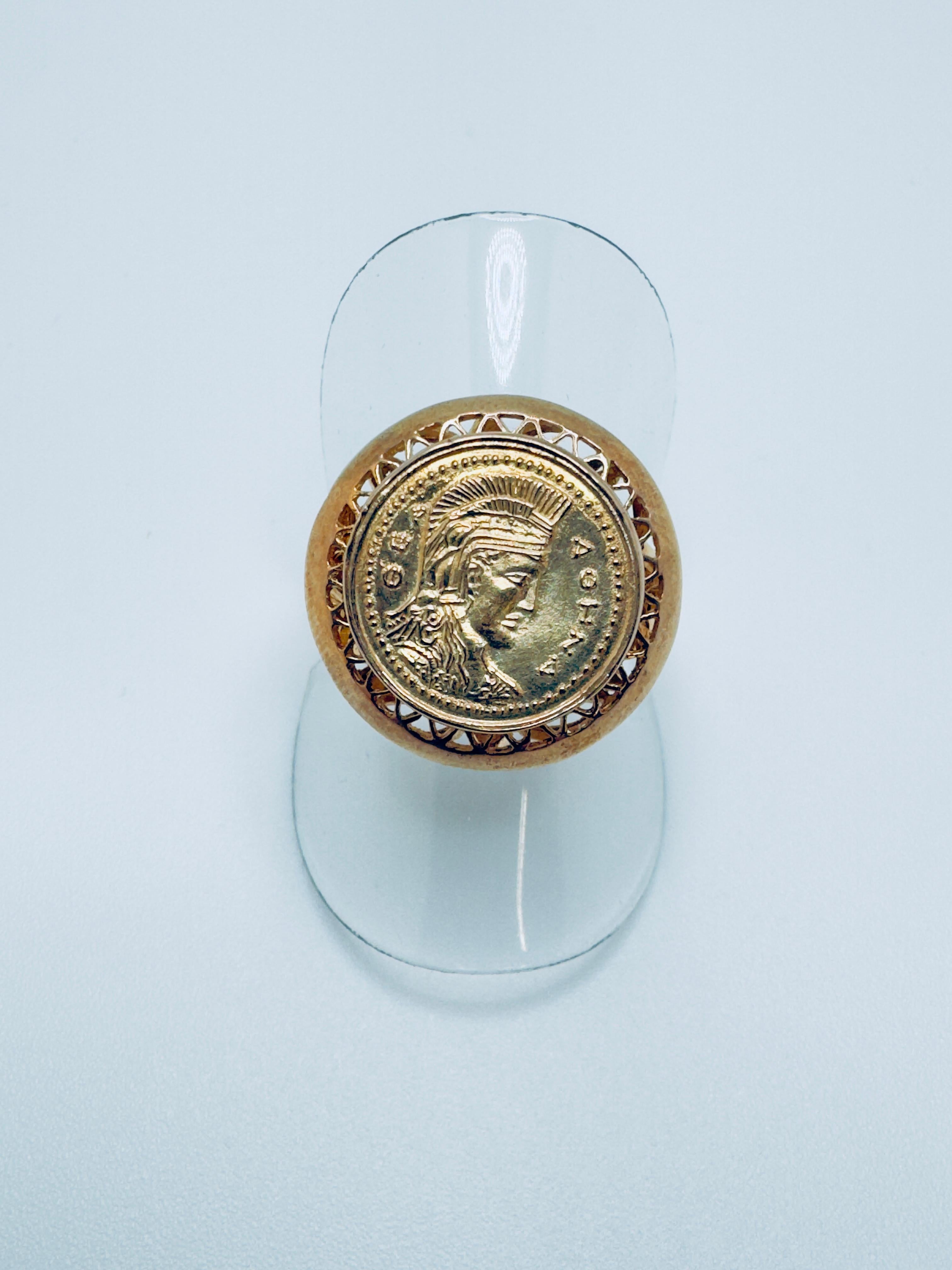 This stylish ladies’ ring is crafted in rich 18 karat yellow gold and showcases a detailed replica of a classic Roman coin at its center. The coin, measuring approximately 14mm in diameter, is framed in a smooth, polished bezel that highlights its