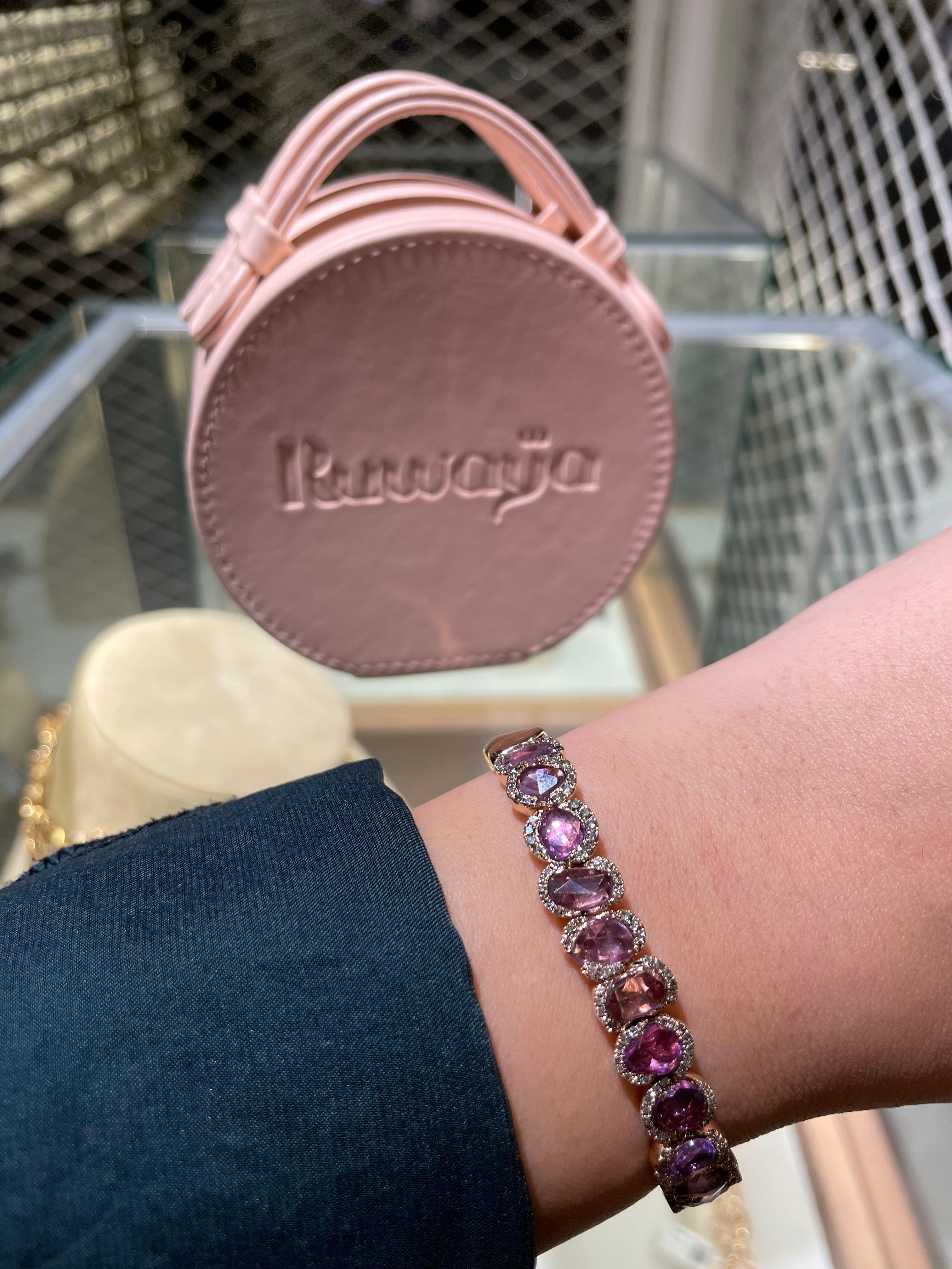 Elevate your jewelry collection with this exquisite open bangle bracelet, handcrafted in 18k rose gold. This elegant piece features a series of vibrant pink sapphires, each uniquely faceted and encircled by delicate round-cut diamonds, adding