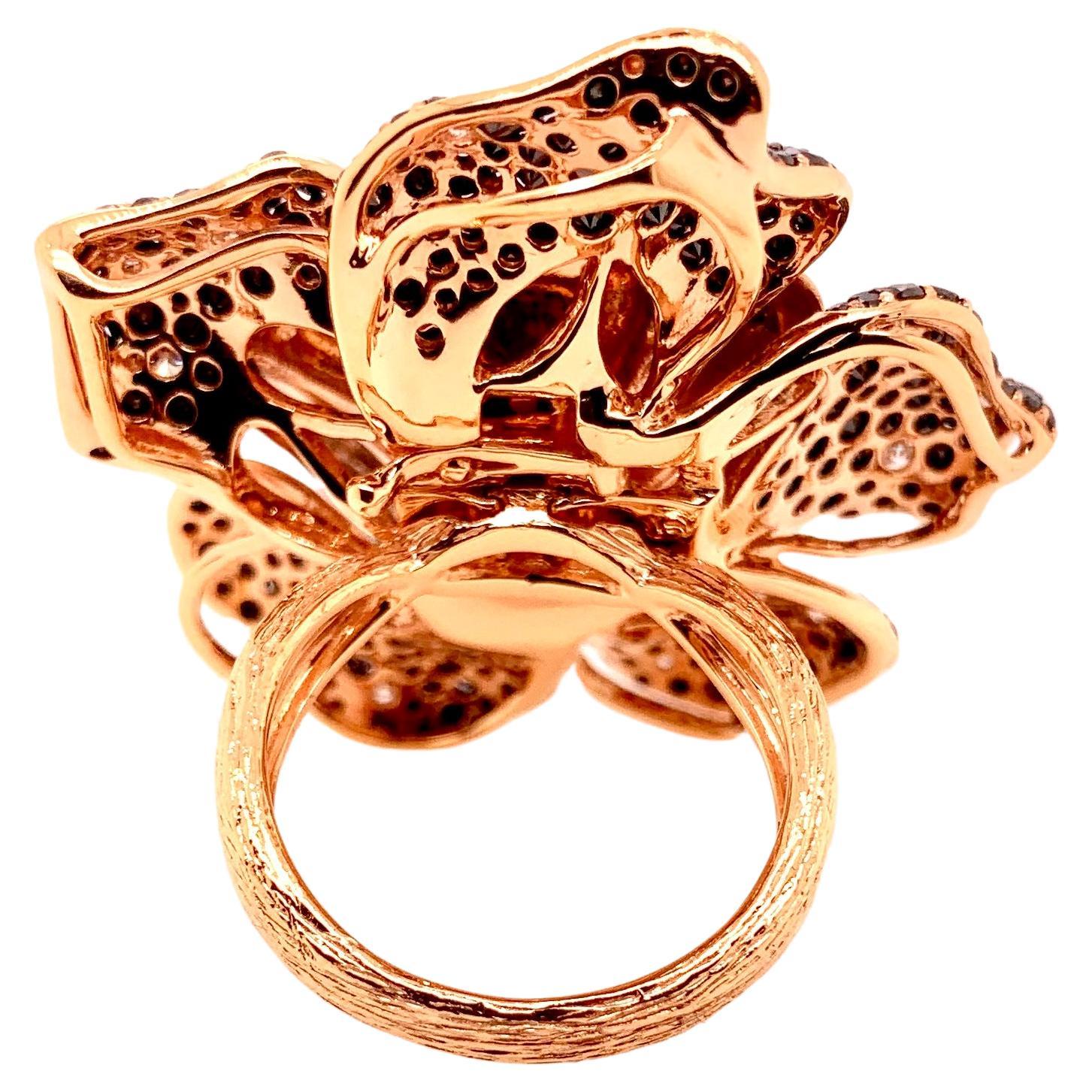 Artigianato superbo!  Questo anello con fiore di rosa in oro rosa 18 carati con diamanti bianchi e neri si trasforma anche in un ciondolo.  I diamanti neri creano un eccellente contrasto con la finitura satinata in oro rosa dei petali.  Anche il