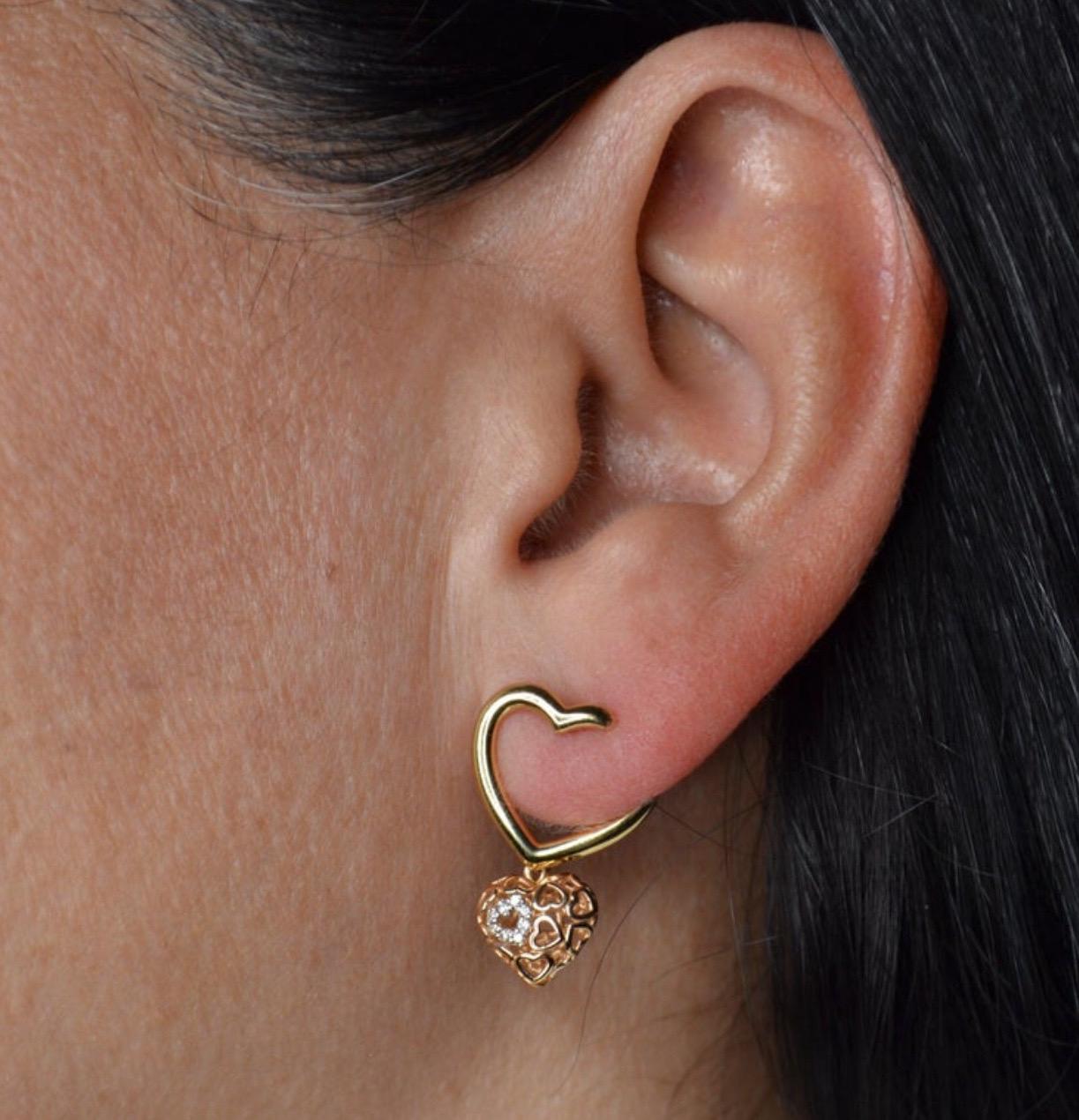 Questi orecchini con charm a forma di cuore sono un romantico mix di oro giallo e rosa, progettato per essere moderno e senza tempo. Il cuore aperto, realizzato in oro giallo lucido, si avvolge leggermente intorno all'orecchio, creando un morbido