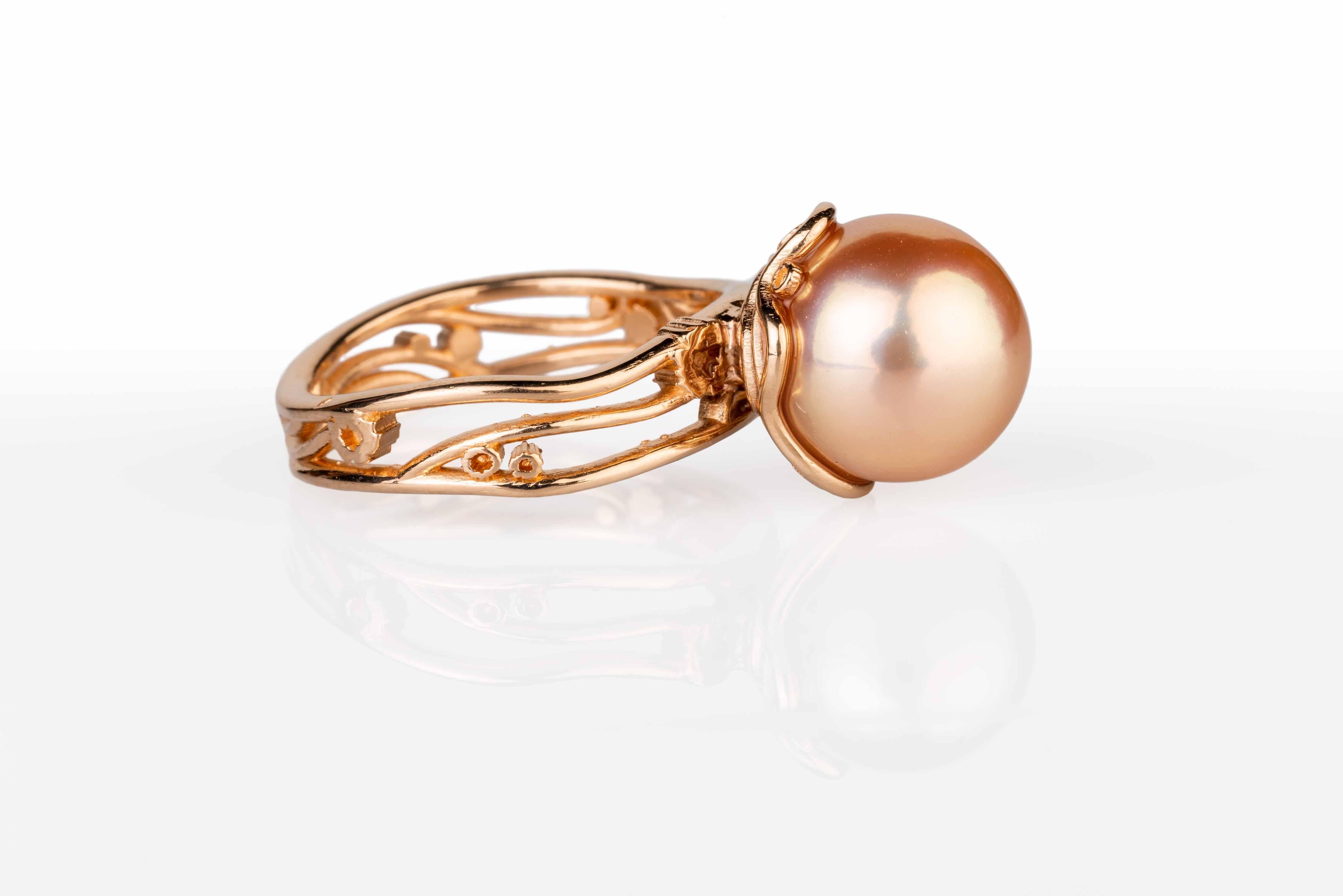 An 18k rose gold ring set with one 10.75mm round freshwater peach colored pearl with a 