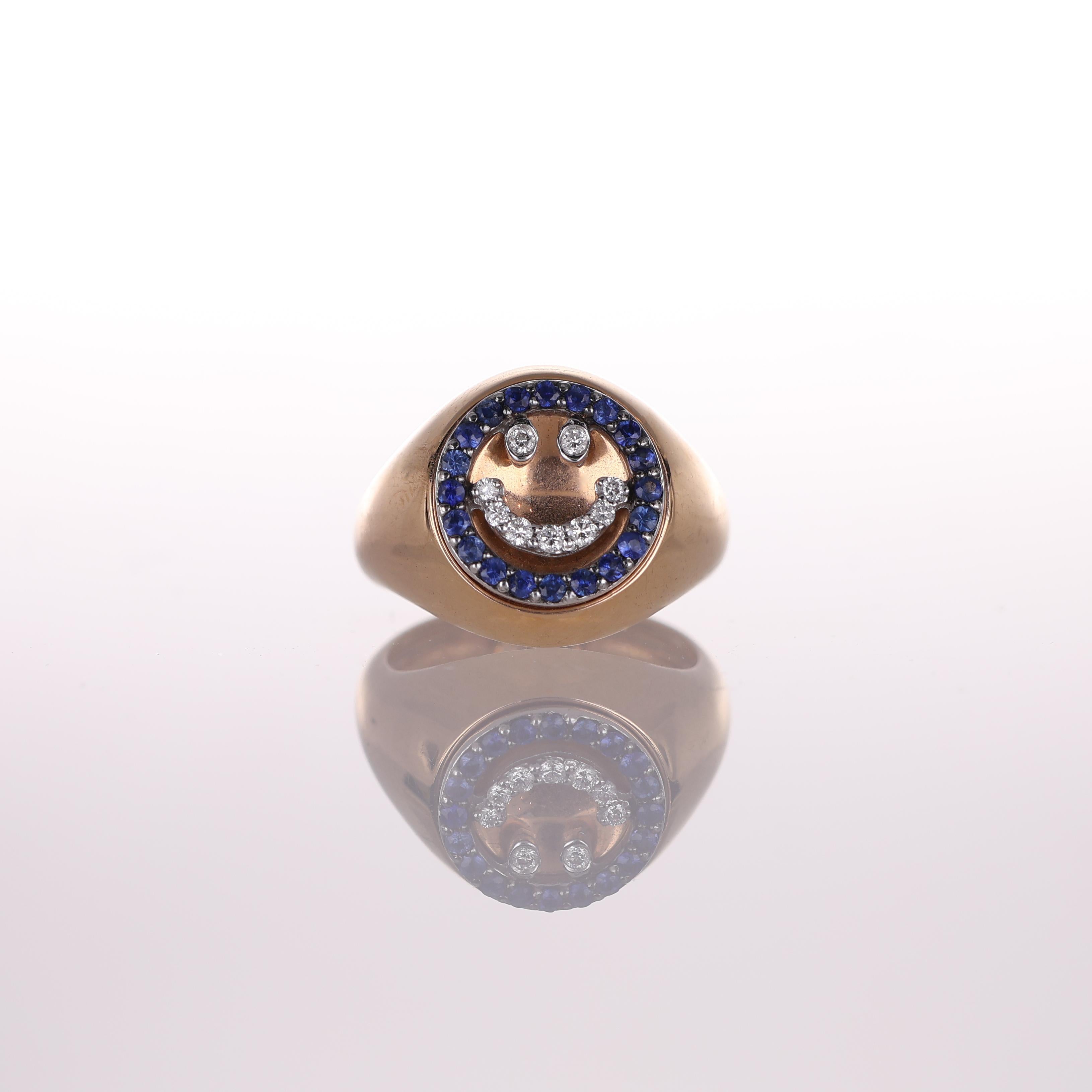 A playful yet refined pinky ring crafted in 18K rose gold, featuring a smiley face motif set with 0.33 carats of brilliant-cut diamonds and framed by 0.26 carats of deep blue sapphires. The combination of warm gold, sparkling diamonds, and vibrant