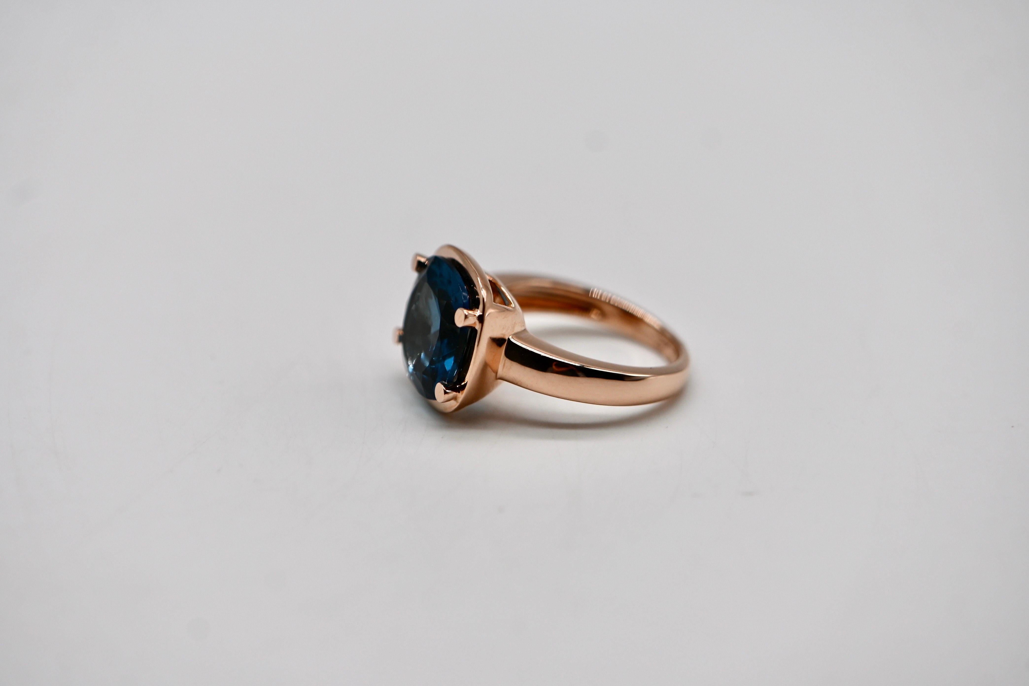 Bold yet refined, this striking ring showcases the perfect balance of soft curves and intense color. Crafted in 18k rose gold, it features a stunning London Blue Topaz, weighing approximately 9.2 carats, held in place by a graceful claw setting. The