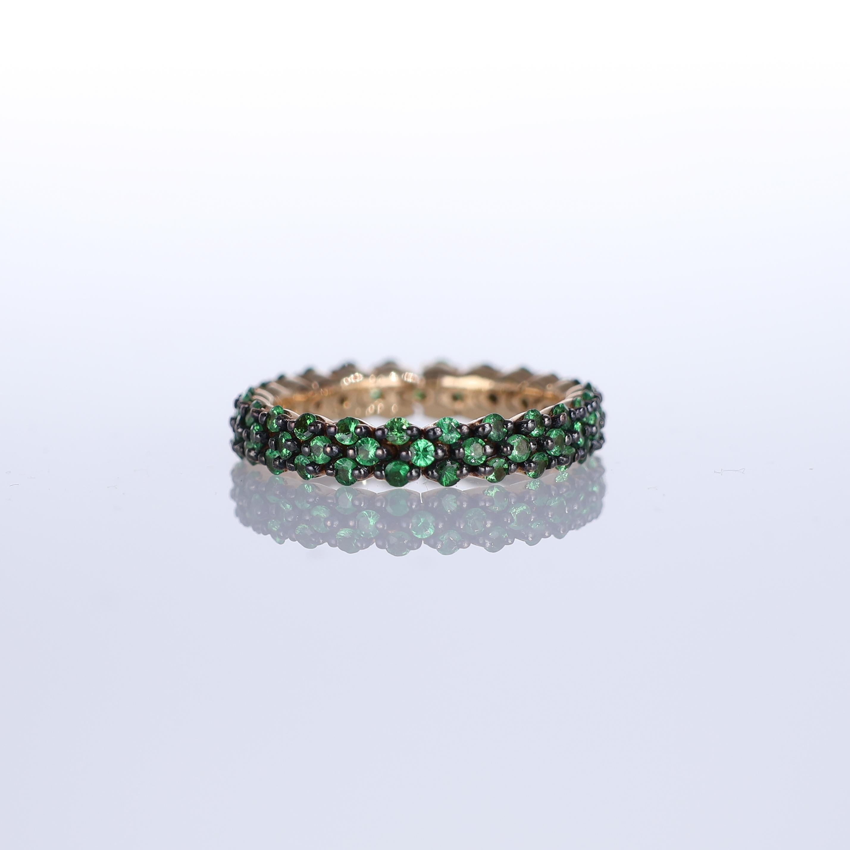 A refined eternity band crafted in 18K rose gold, adorned with 1.33 carats of vibrant green tsavorite garnets. The deep, rich hue of the gemstones contrasts beautifully with the warmth of the gold, creating an elegant yet distinctive piece. Designed