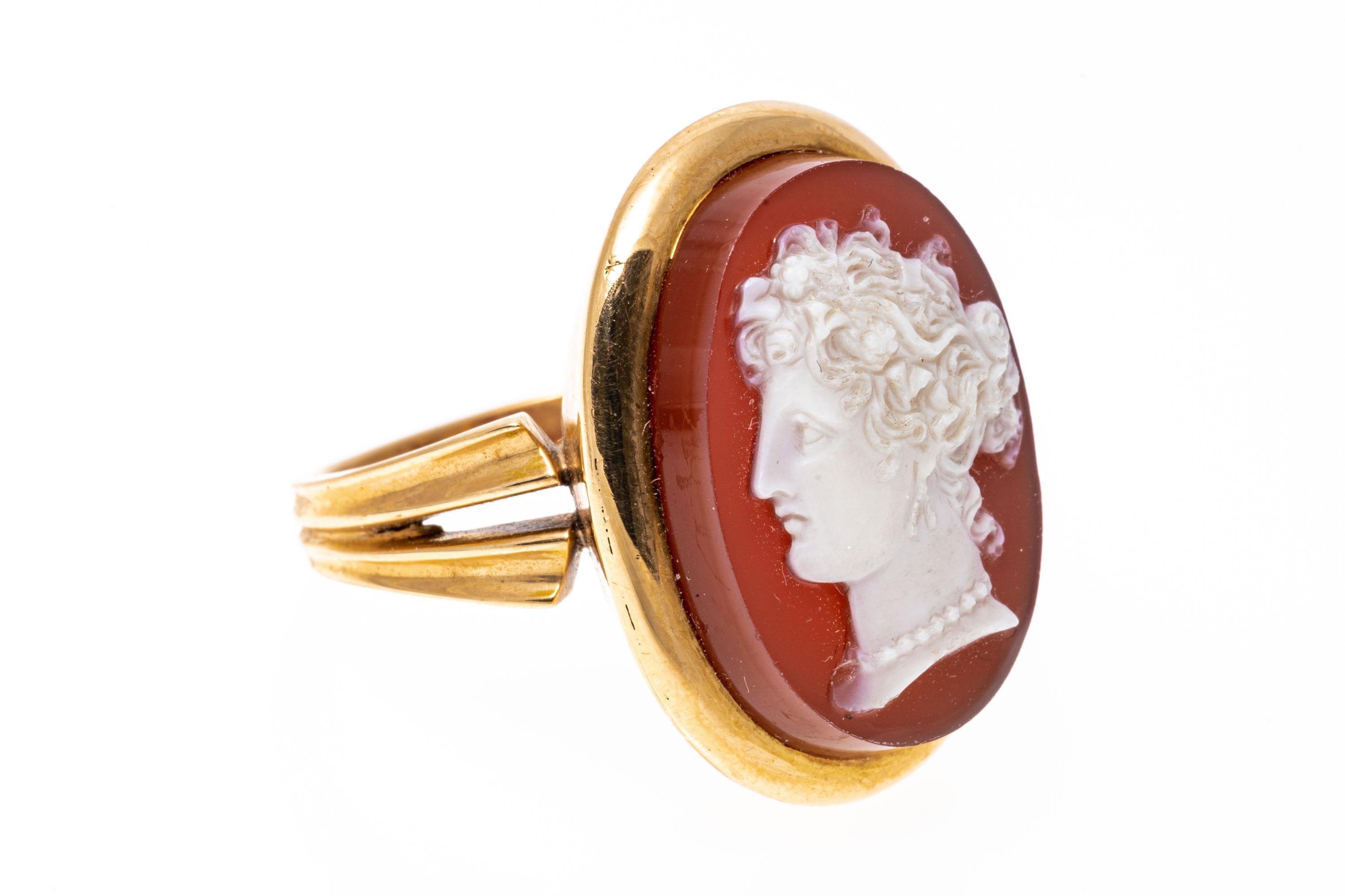 18k rose gold ring. This beautiful vintage oval cameo ring has an orange background with a creamy white foreground of a handsome classic silhouette, facing to the left, and set off with a wide, high polished frame. The ring is also adorned with a