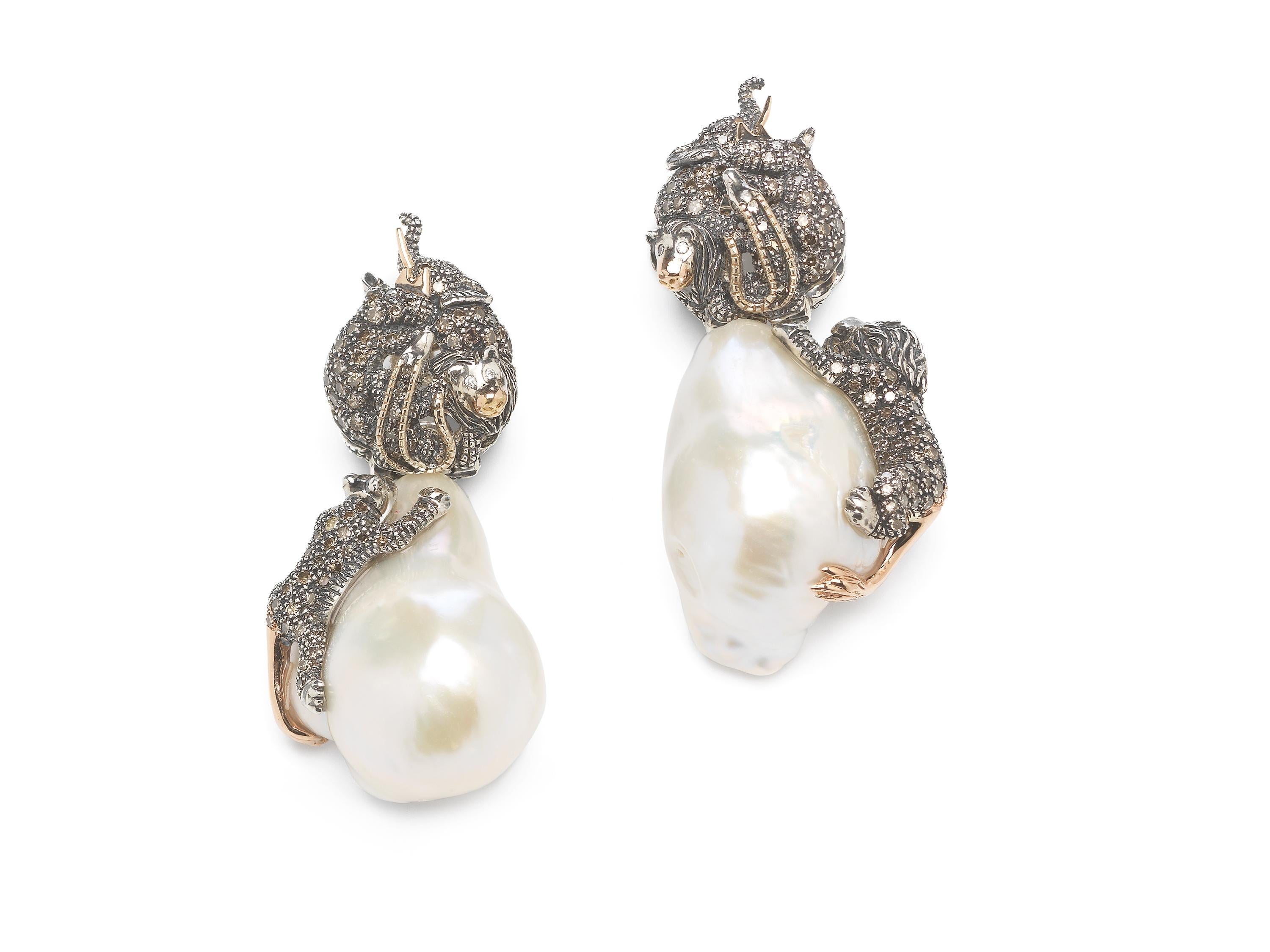 Two beautiful baroque pearls are the focal point of these drop earrings, with the pearls set with animals that appear to crawl up their irregular surface. The animals shown here are male and female lions, but the creatures can be customised to