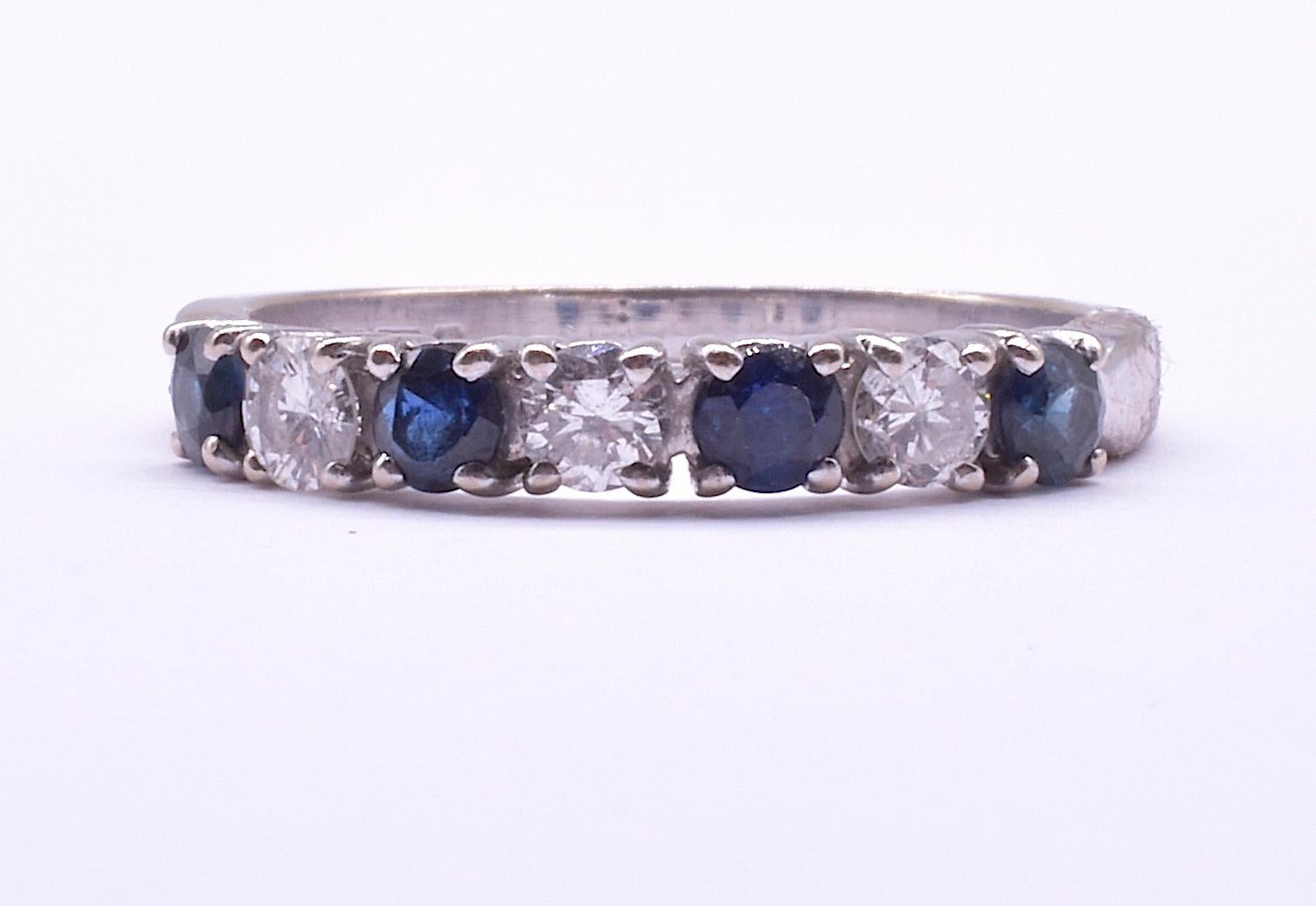 Our vintage 1/2 hoop 7 stone ring is hallmarked 18K London for the year 1975. With 4 sapphires and 3 diamonds it is the perfect ring to pair with other bands. Approximately 4 mm in width, the ring has a somewhat modern geometric look with round