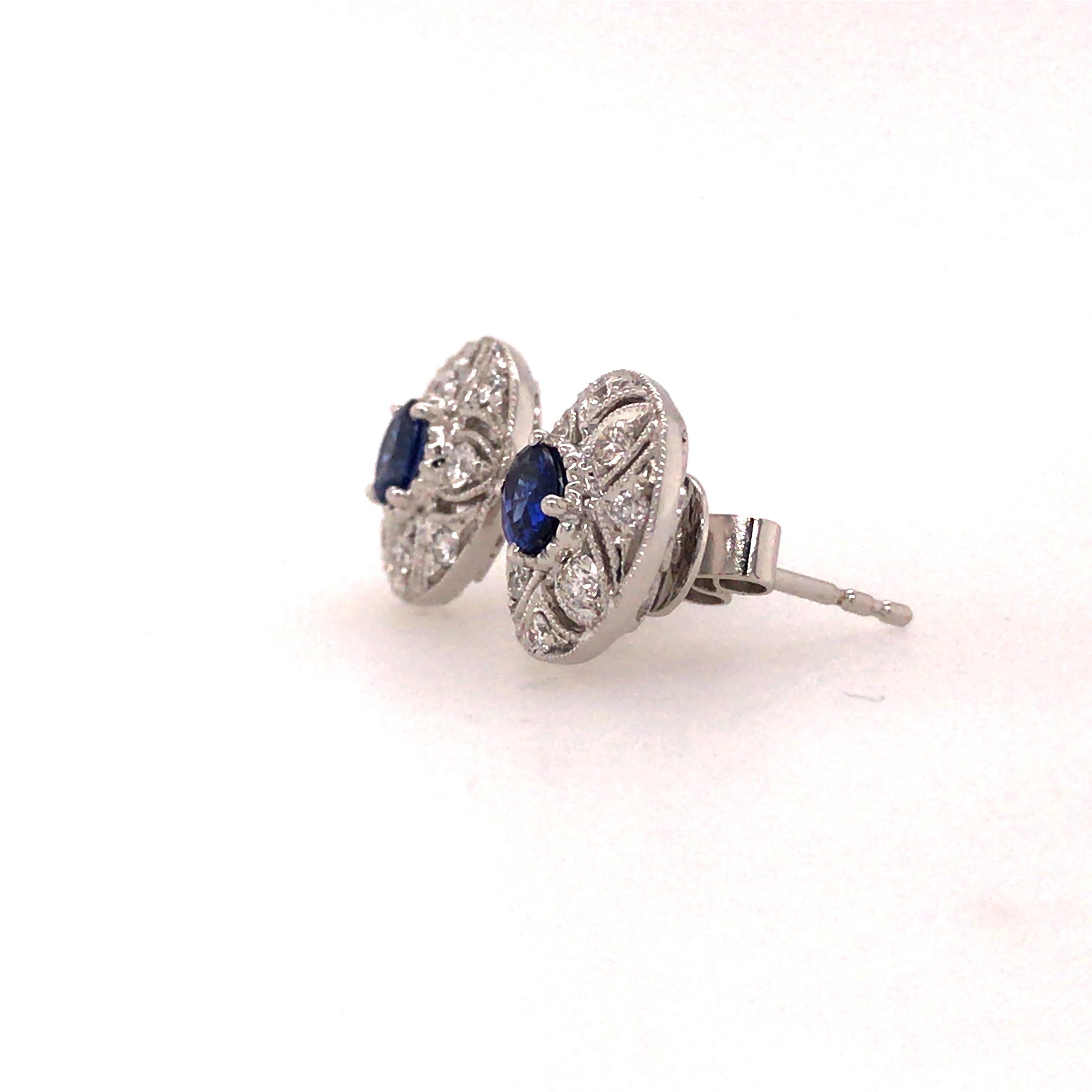 A classic beautiful pair of Sapphire and Diamond cluster earrings in 18K White Gold.  (2) Sapphires weighing .41 carat total weight are bezel set and surrounded by (16) Round Brilliant Cut Diamonds weighing .25 carat total weight, G-H in color and