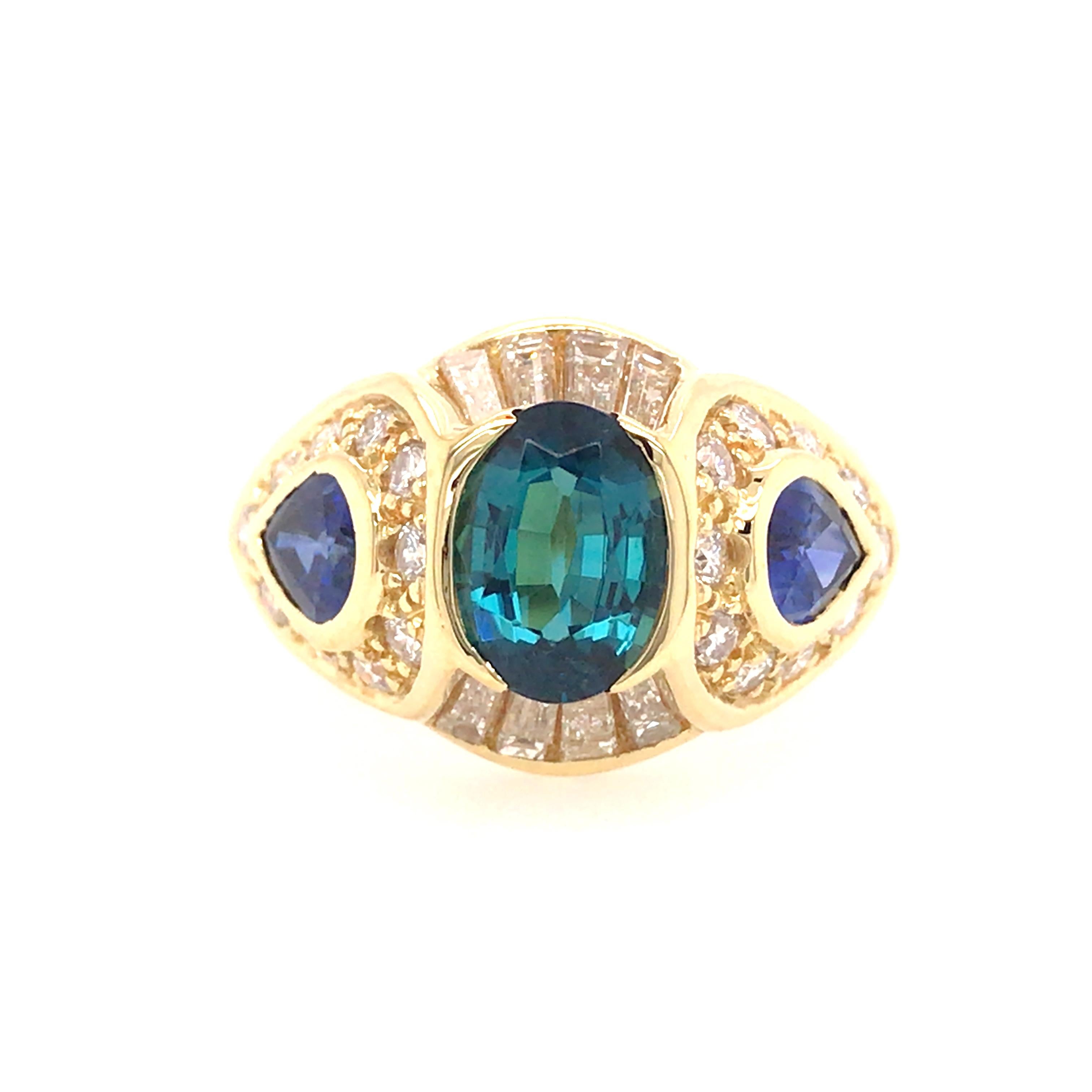 Sapphire and Diamond Ring in 18K Yellow Gold.  Baguette and Round Brilliant Cut Diamonds weighing 1.04 carat total weight, G-H in color and VS in clarity and (3) Sapphires weighing 2.50 carat total weight, including 1.30 carat center are expertly