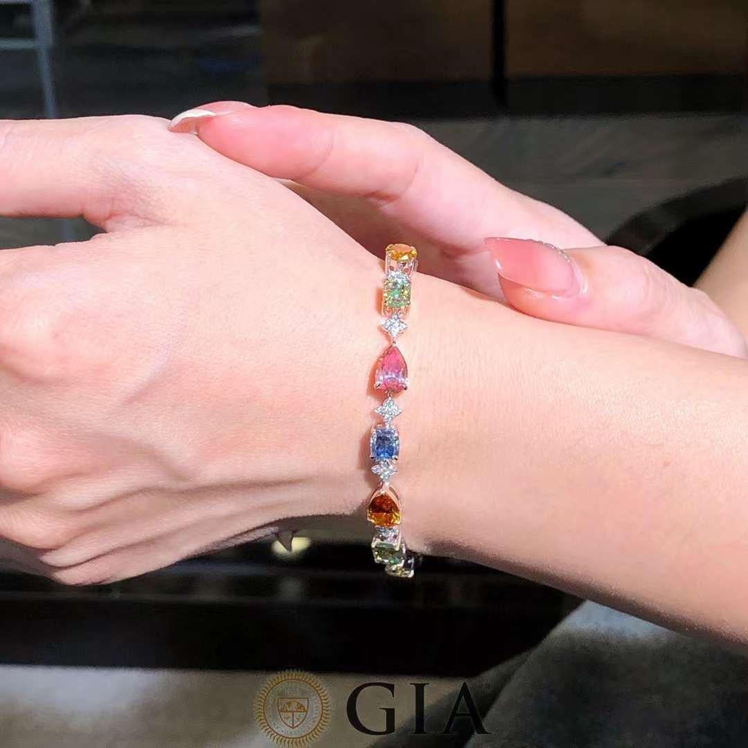 This 18K solid gold bracelet features 14.40 carats of GIA certified natural colored diamonds, artfully arranged in a harmonious composition of mixed shapes and vibrant hues. Each diamond is hand-selected for its brilliance, saturation, and clarity,