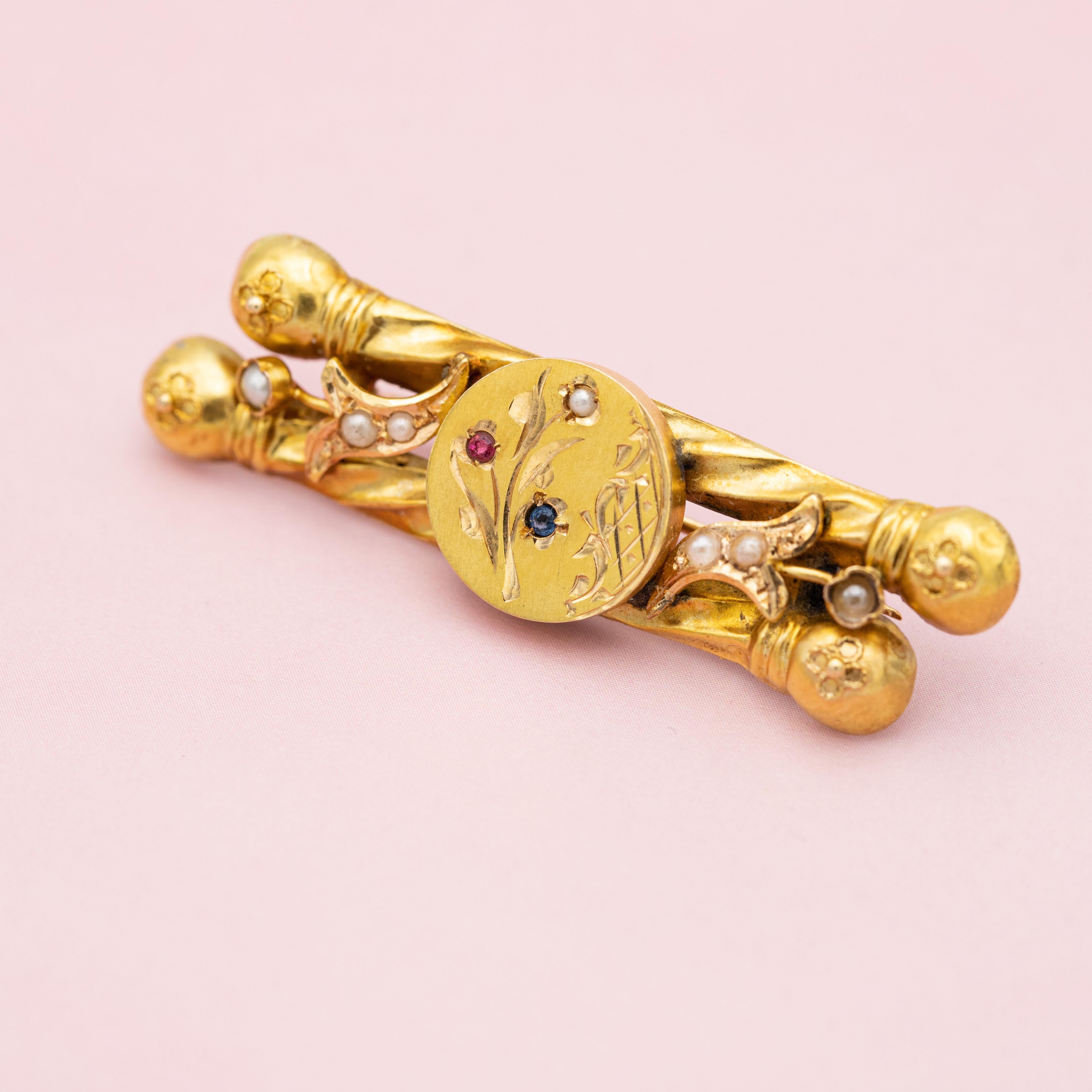 This wonderful Victorian bar brooch comes directly from the floral Art Nouveau period. This antique brooch features two twisted bars with balls on the end, each ball is covered with little flowers. A round plate holds the two twisted bars together.