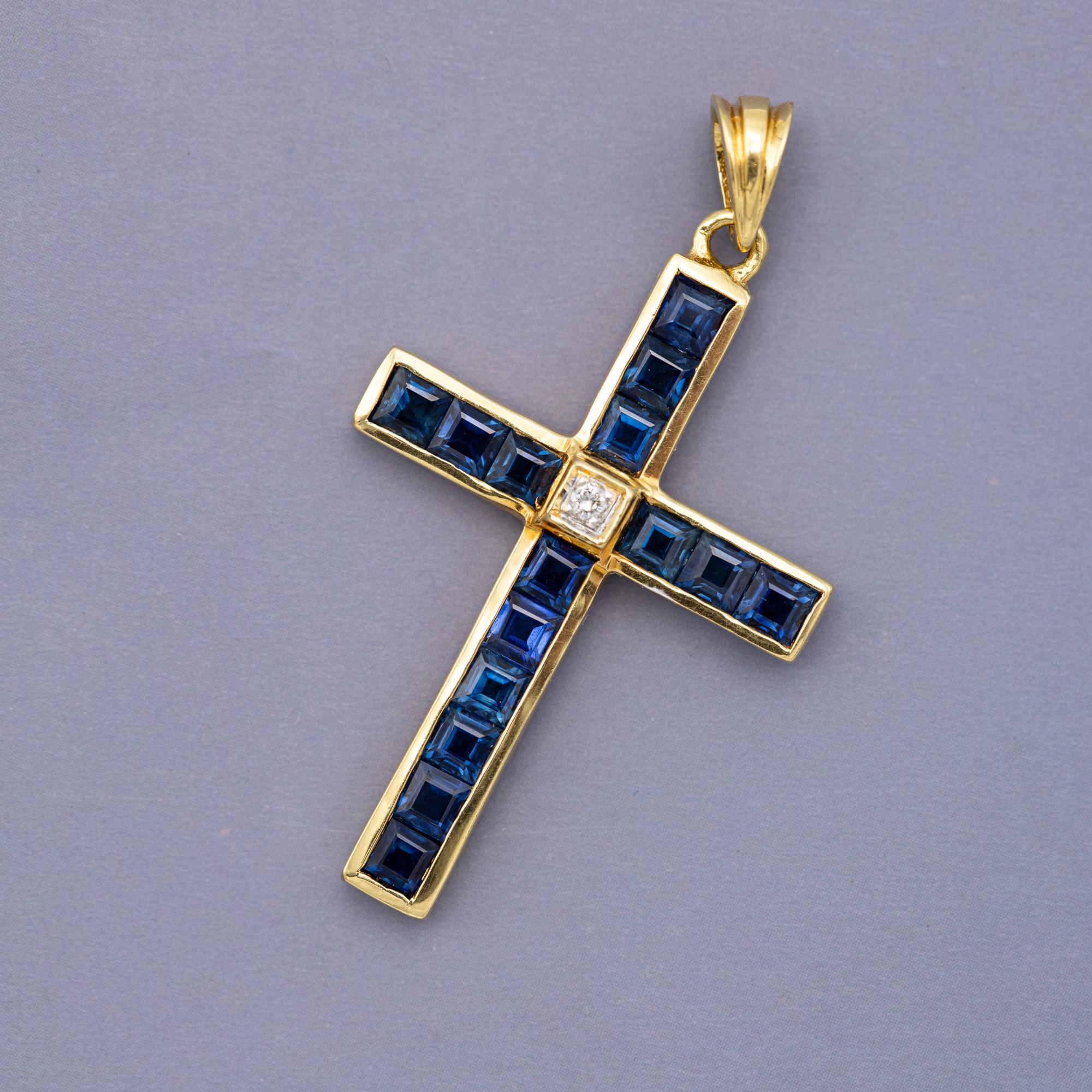 For sale is this wonderful 18 Karat yellow gold cross pendant. This beautiful charm is covered with fifteen carré cut sapphires which combine for 1,5 ct. These deep blue gemstones are placed in the shape of a cross, with in their centre a small