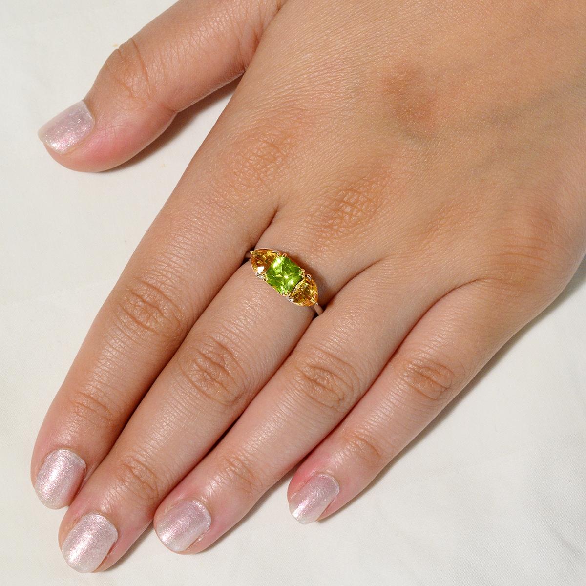 An EK Designs original this bold and distinctive ring features an alluring peridot gemstone flanked by golden citrines in 18K solid gold. The 1.80 carat natural asscher cut peridot measures 6.50mm by 6.50mm and sits in a unique 18k yellow gold