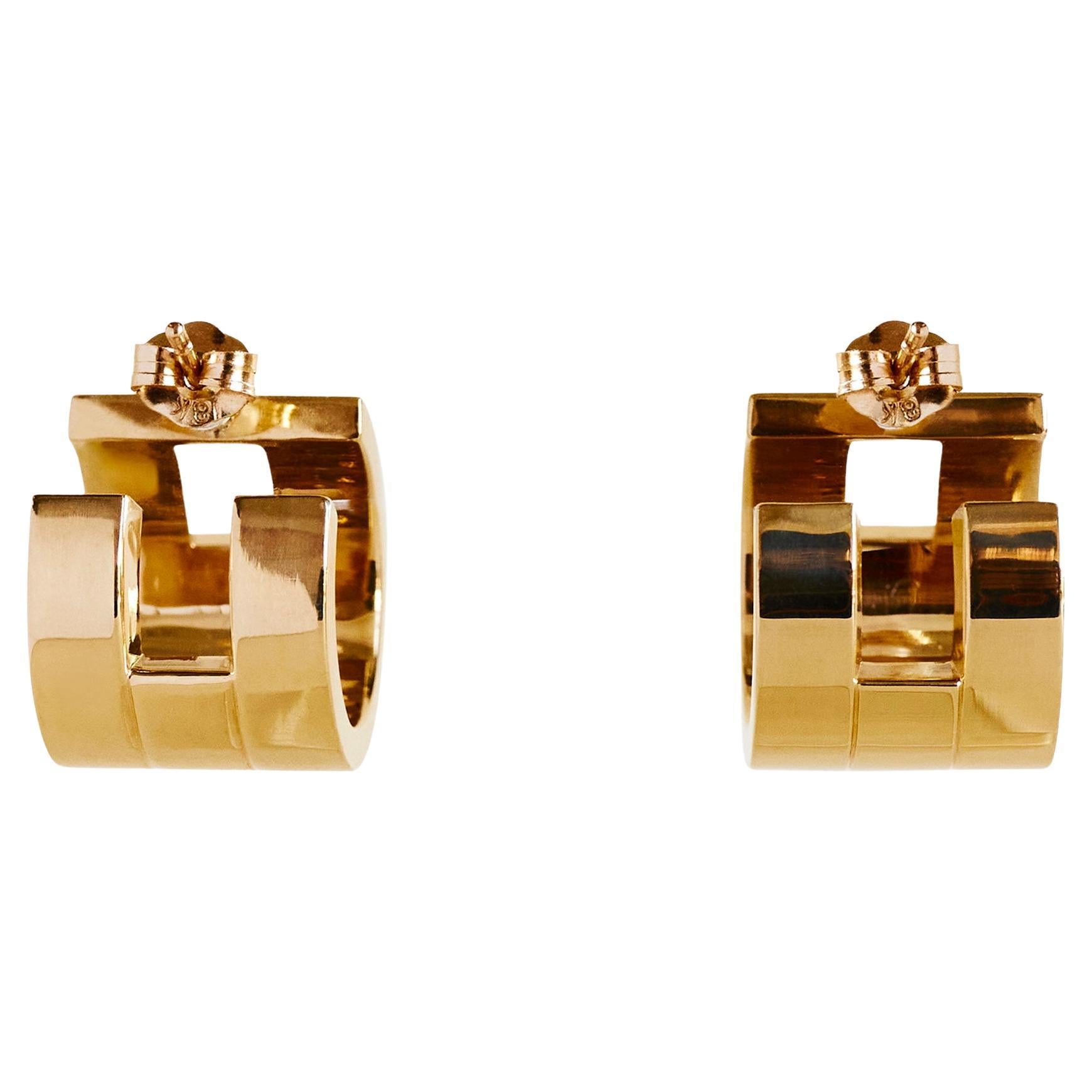 Les boucles d'oreilles Margueritte : Compactes mais audacieuses, les boucles d'oreilles Margueritte réinterprètent le langage sculptural de la manchette Margueritte en une paire d'anneaux architecturaux et épais. Fabriqué en or massif 18 carats,