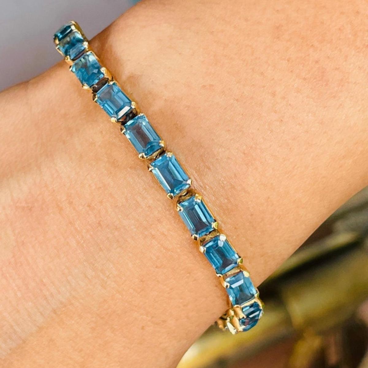 This 18.5 ct Blue Topaz Tennis Bracelet in 18K gold showcases 25 endlessly sparkling natural blue topaz, weighing 18.5 carats. It measures 7.25 inches long in length. 
Blue topaz helps to improve communication and self expression. 
Designed with