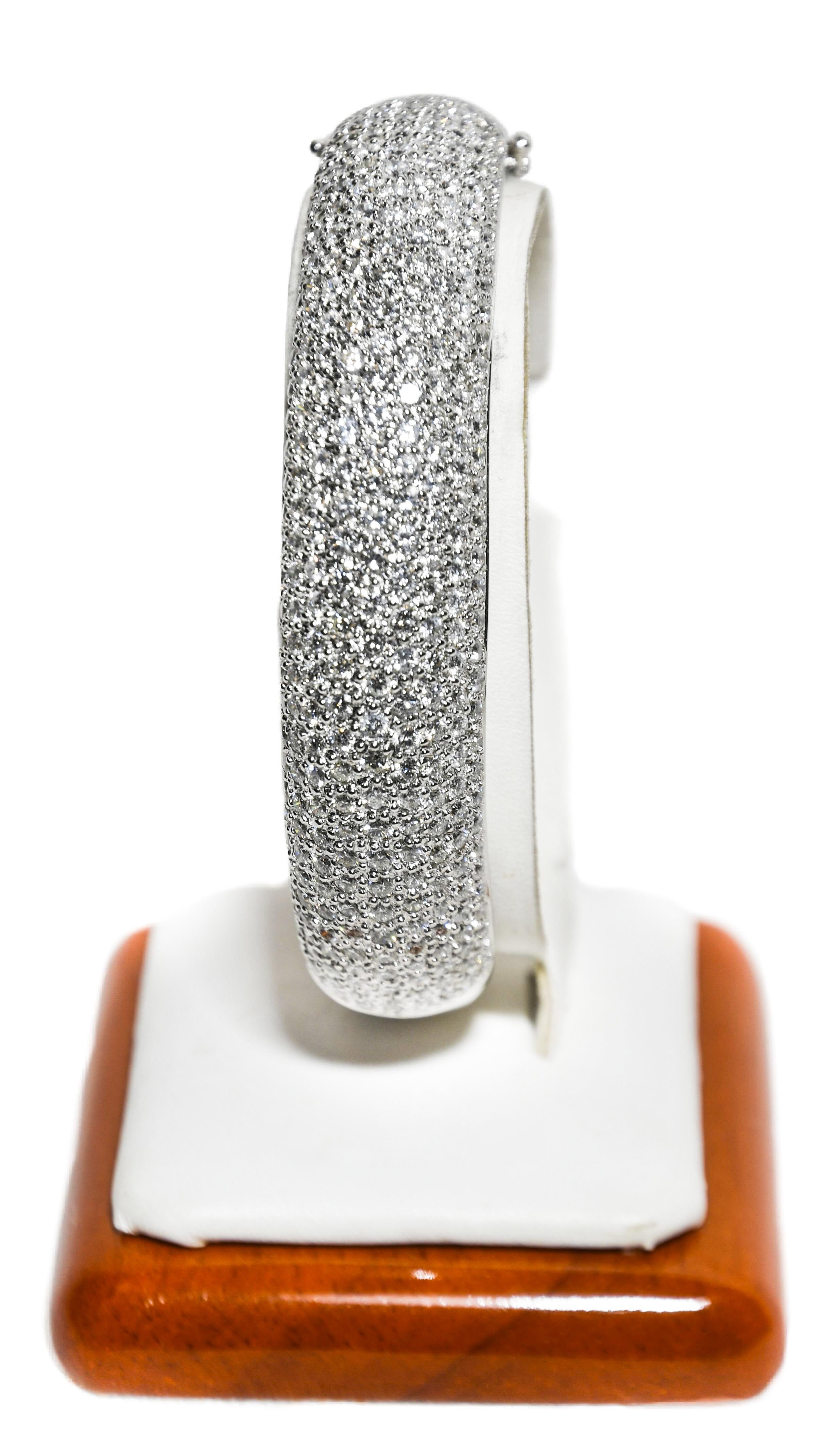  Artfully crafted in 18 Karat white gold, this domed top hinged bangle has over the top quality and weight!  Boasting 23.55 carats total weight of hand set brilliant cut diamonds meticulously selected in F color, VVS clarity.  Kindly look closer at