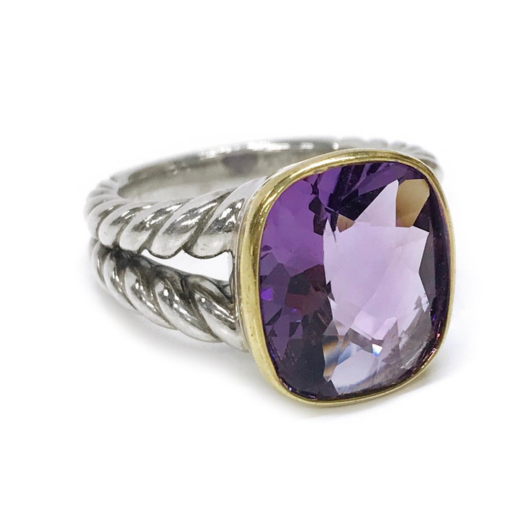 Two-tone 18 Karat yellow gold and sterling silver David Yurman Amethyst Ring. The ring features the distinctively Yurman cable split band with a faceted purple Amethyst bezel set in 18K yellow gold. Stamped on the inside of the band is D.Y. 925 750.