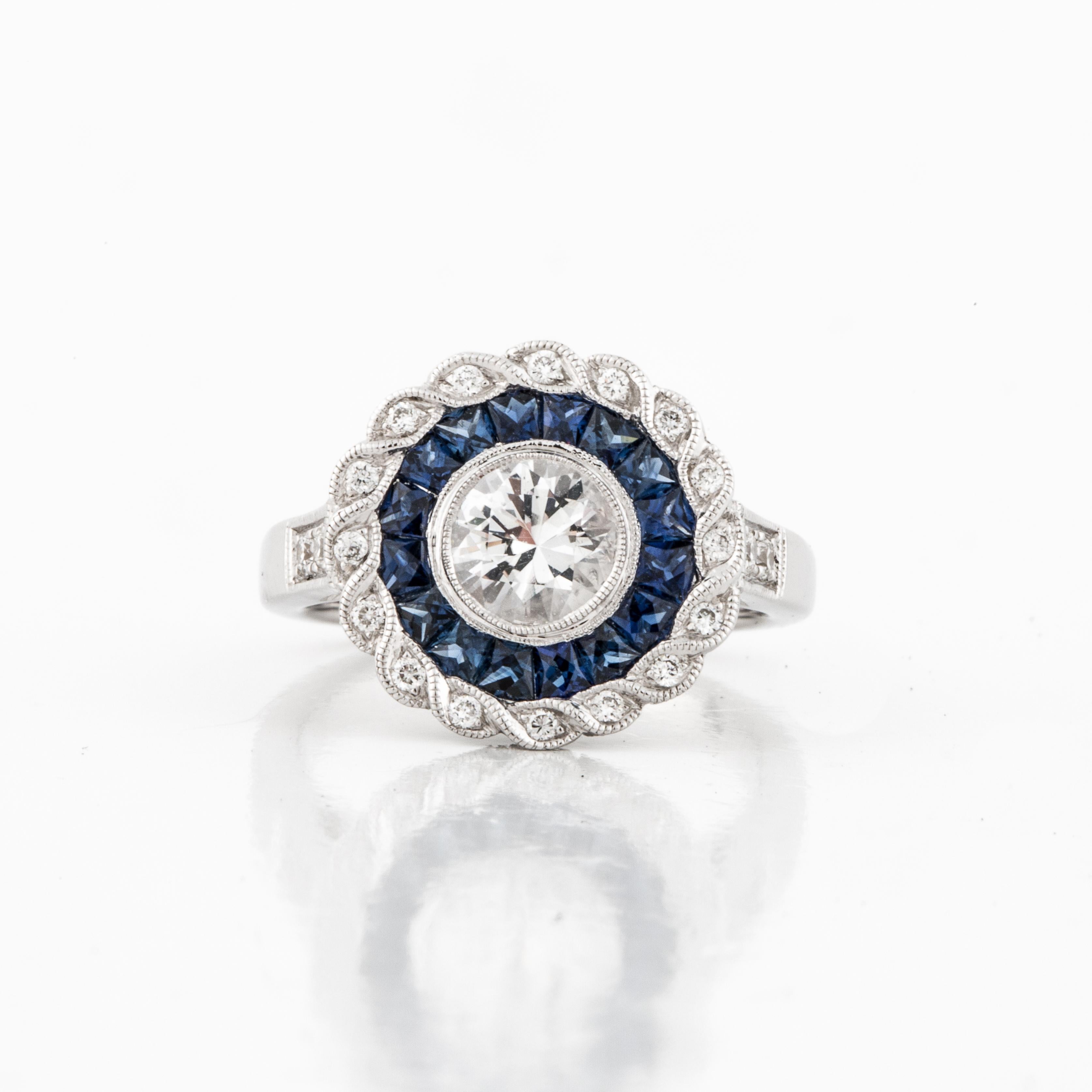 Modern version of a vintage target ring in 18K white gold.  The center stone is a colorless beryl weighing 0.75 carats.  Surrounding the beryl are 16 blue sapphires with a total carat weight of 0.65.  The outside border contains 20 round diamonds