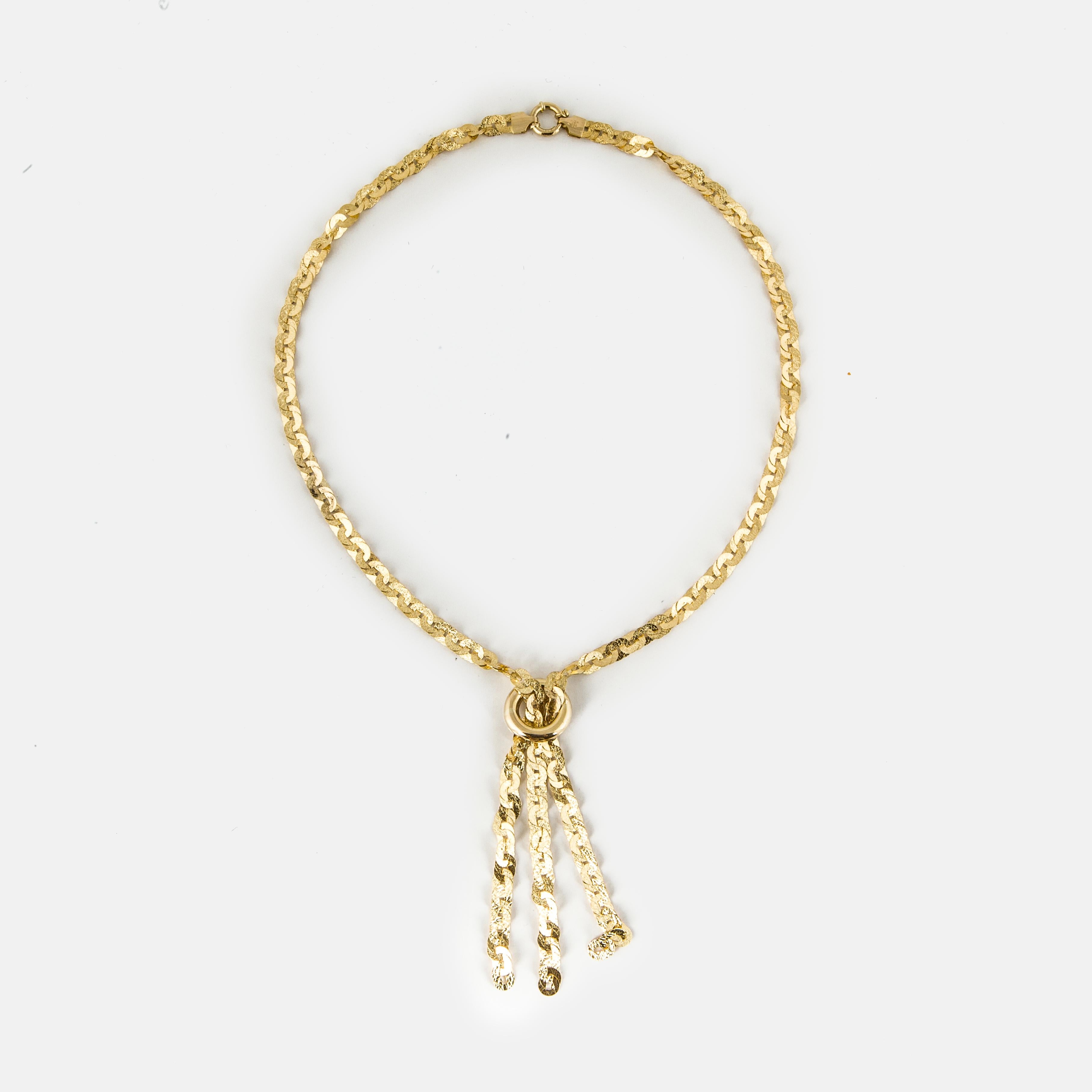 18K yellow gold link necklace with a tassel.  The links are small ovals of gold and are engraved.  Hanging from the bottom is a tassel made of the same chain.  Necklace measures 17