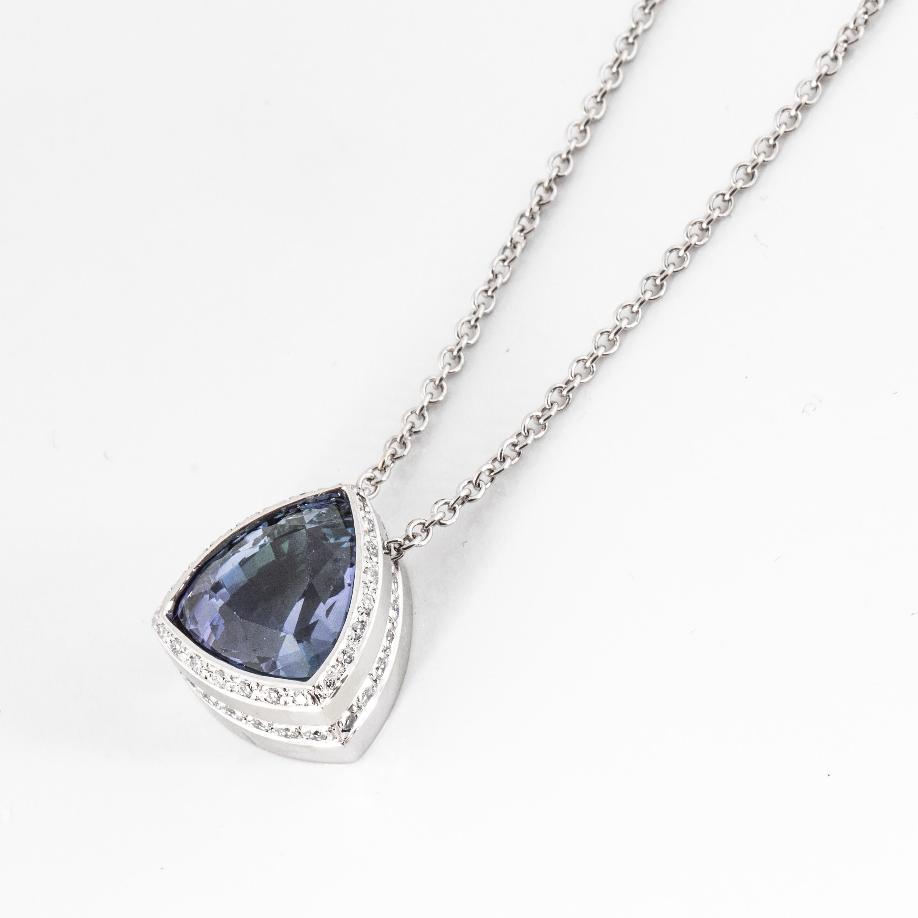 18K white gold pendant necklace featuring a triangular tanzanite with a diamond halo.  The tanzanite totals 5 carats.  There are 44 round brilliant-cut diamonds that total 0.35 carats; G-H color and VS clarity.  The chain is 14K white gold and