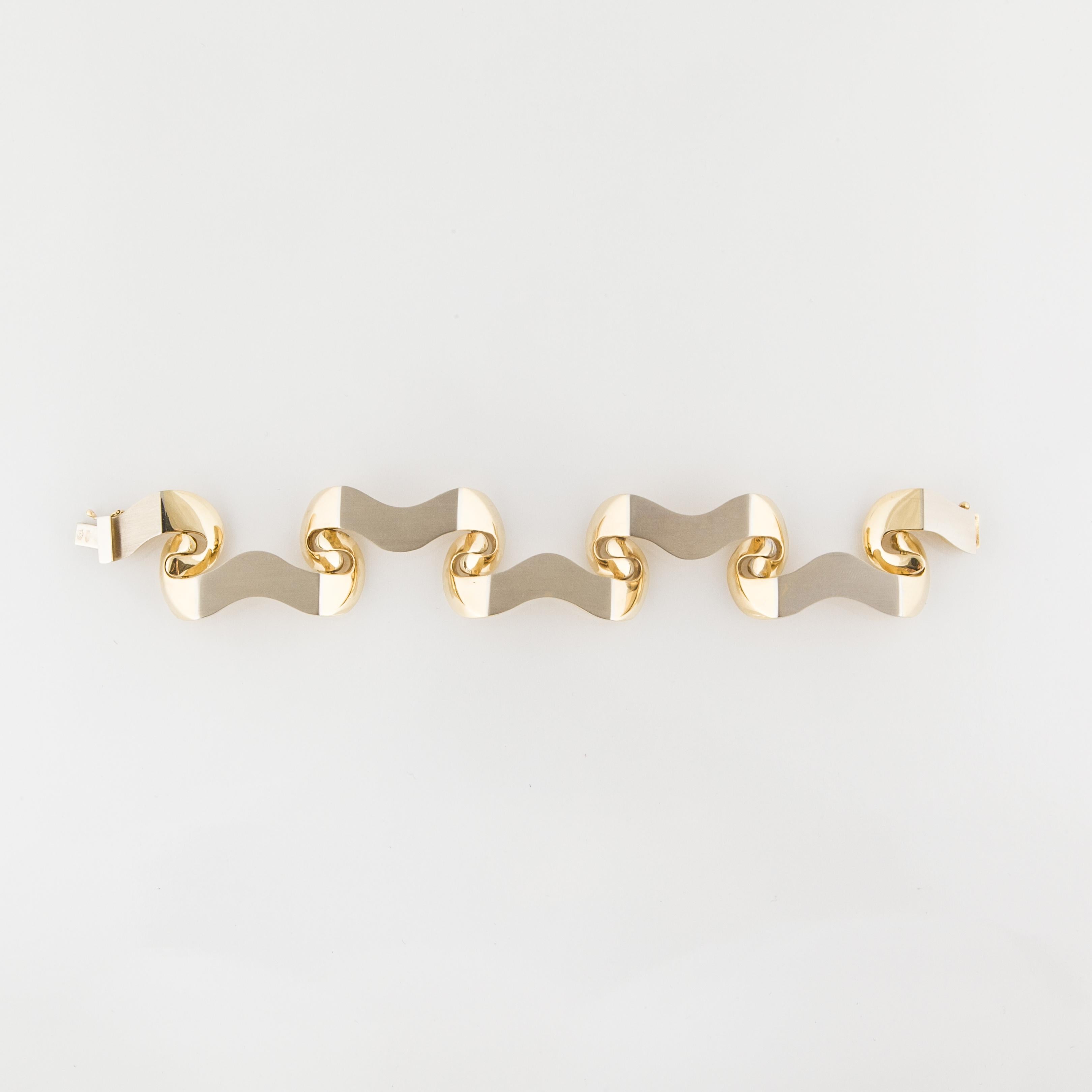 18K two-tone gold bracelet features both brushed and high polished finishes.  When the bracelet is fastened, it wears like a bangle.  It is a unique design, fine quality.  The bracelet measures 7 3/4 inches long and 1 1/8 inches wide.  Italian.