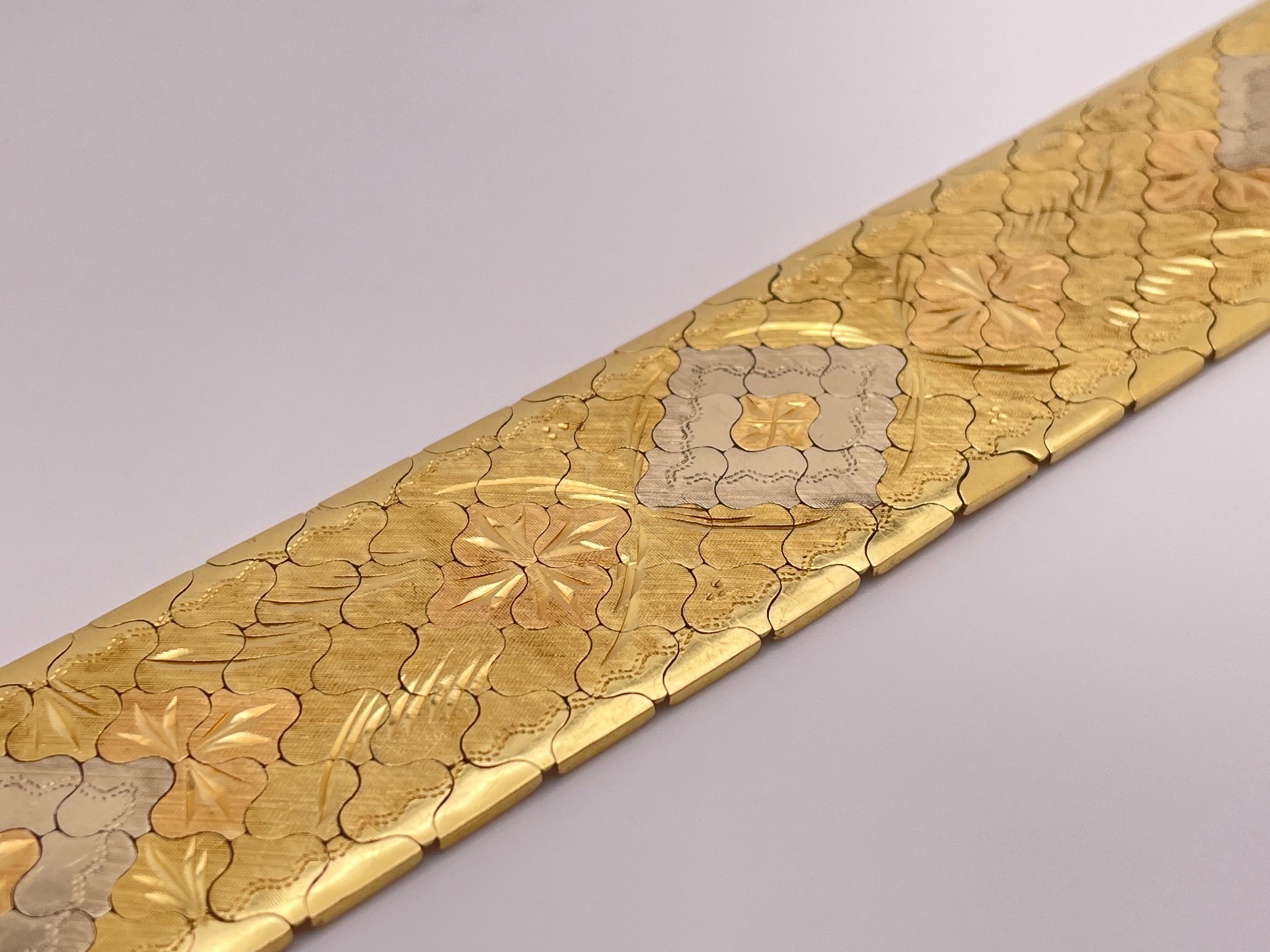 An original 18K yellow and white gold two-tone textured flexible wide bracelet, featuring a magnificent and unique carved design, circa 1970s. Made up of many individually shaped curved panels, each fitting together perfectly creating waves when