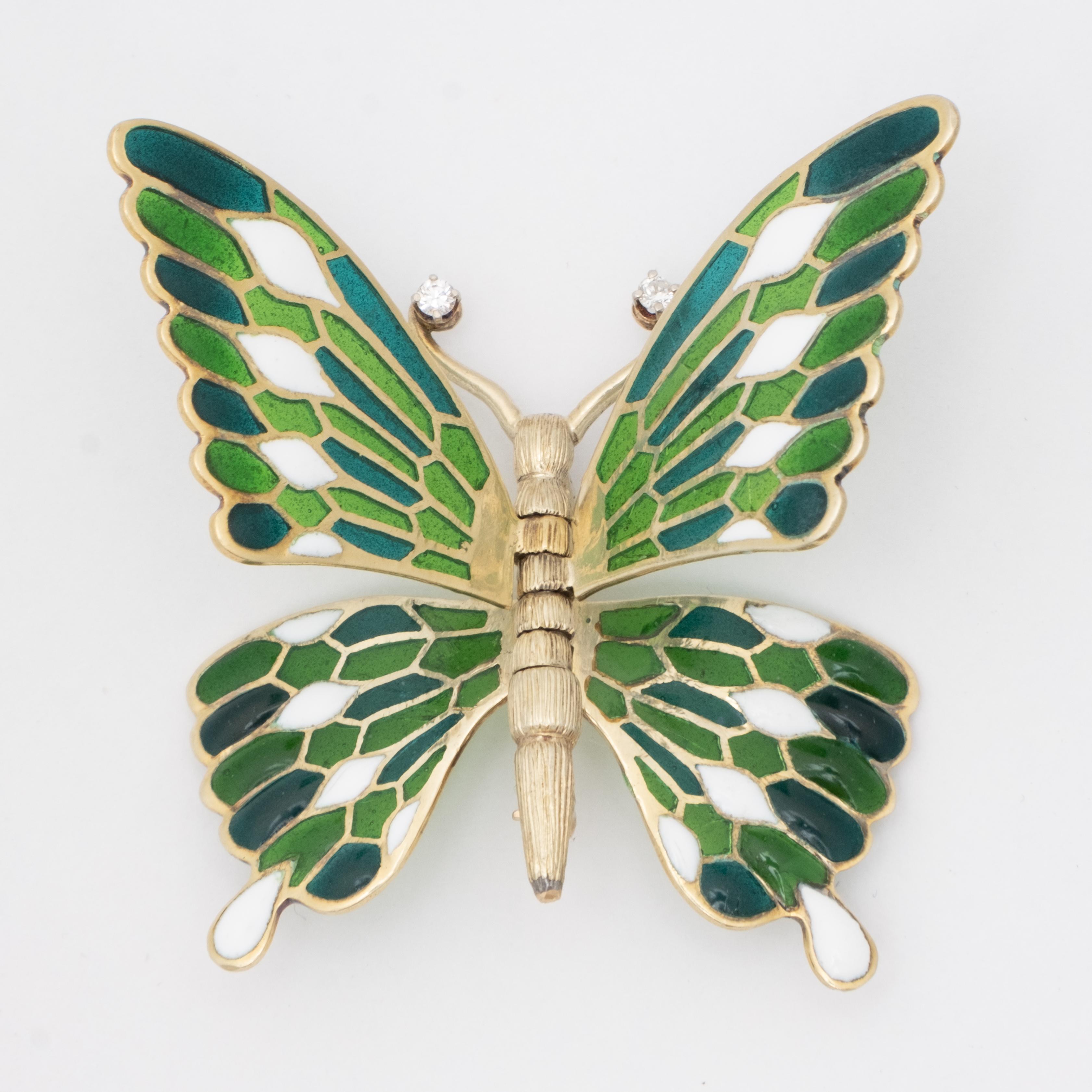 An elegant 18k plique-à-jour diamond butterfly brooch with hinged wings. A single diamond at the end of each antenna. The enameled wings swivel on the body of the butterfly, which is florentine in style, allowing various configurations of wings,