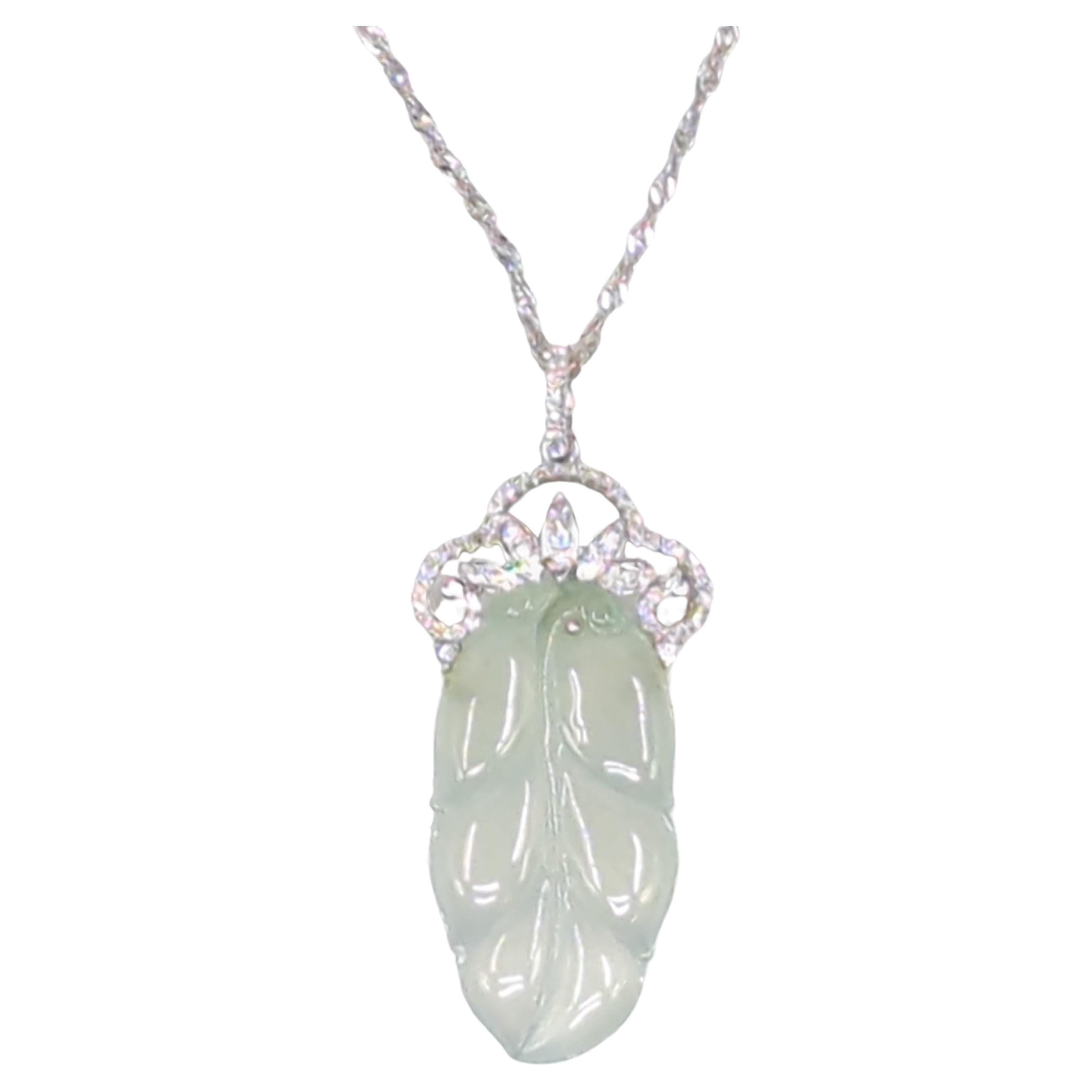 This elegant ladies' pendant featuring 18K white gold is set with a finely carved very pale green icy jadeite leaf pendant (6.22gr). The jadeite exhibits a semi-transparent quality and is finely polished, and set with 55 round brilliant cut diamonds