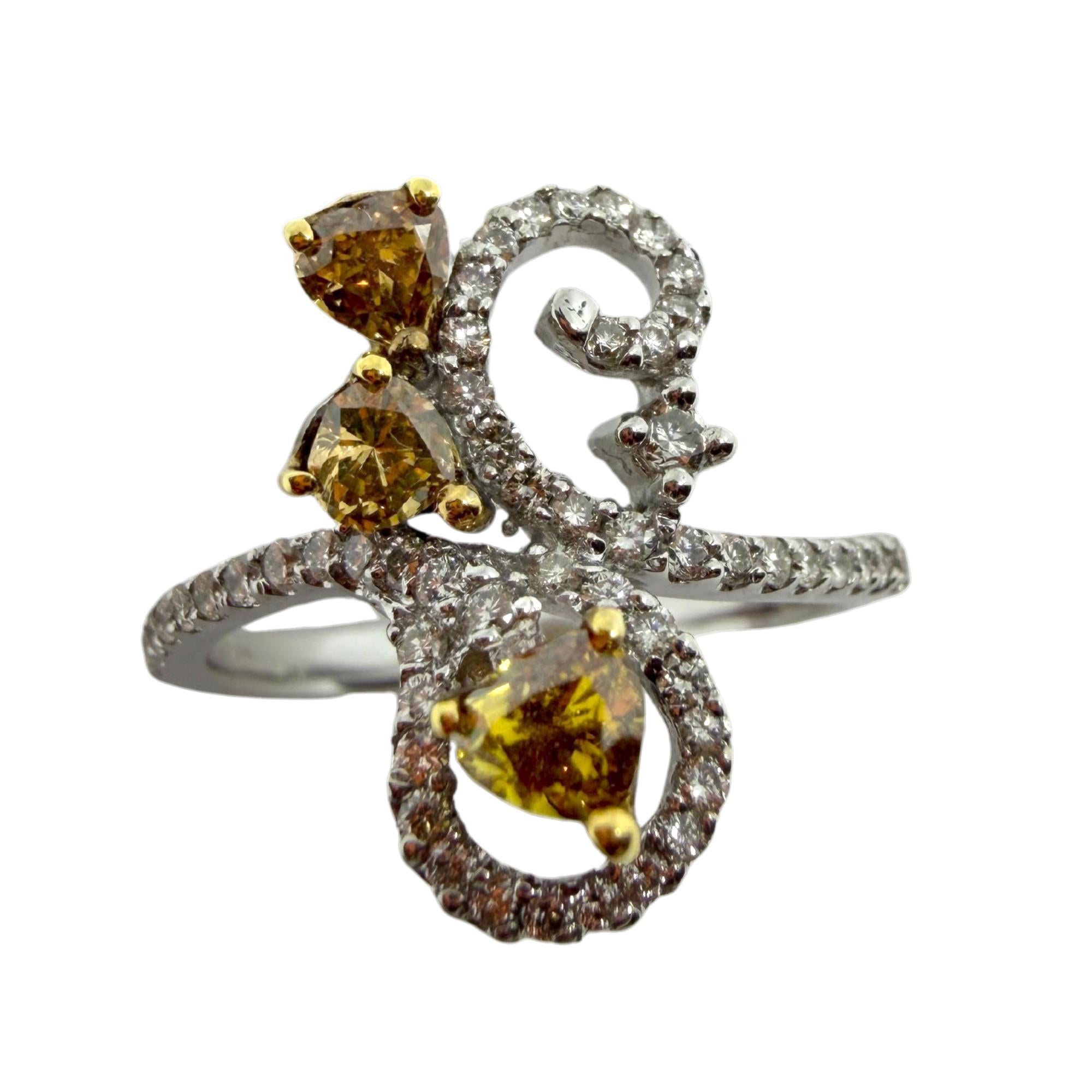 Questo anello in oro bianco 18 carati ha un design divertente e fluente con diamanti bianchi scintillanti e tre caldi diamanti marroni incastonati in rebbi d'oro giallo. Il mix di tonalità gli conferisce un contrasto fresco che cattura la luce in