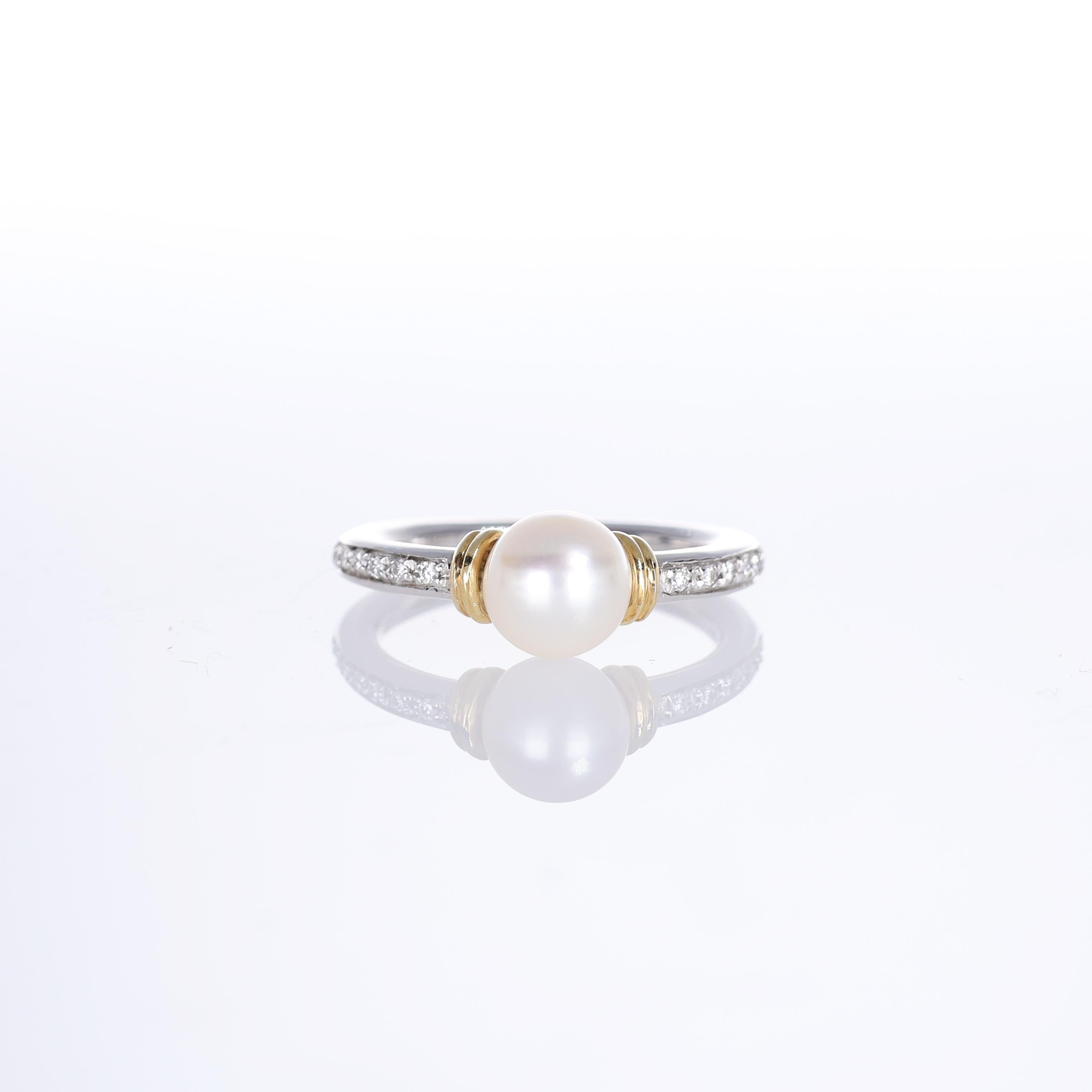 A refined ring crafted in 18K white and yellow gold, featuring a luminous central pearl. The band is adorned with two rows of pavé-set natural white diamonds, enhancing the elegance of the design. The contrast between the gold tones and the